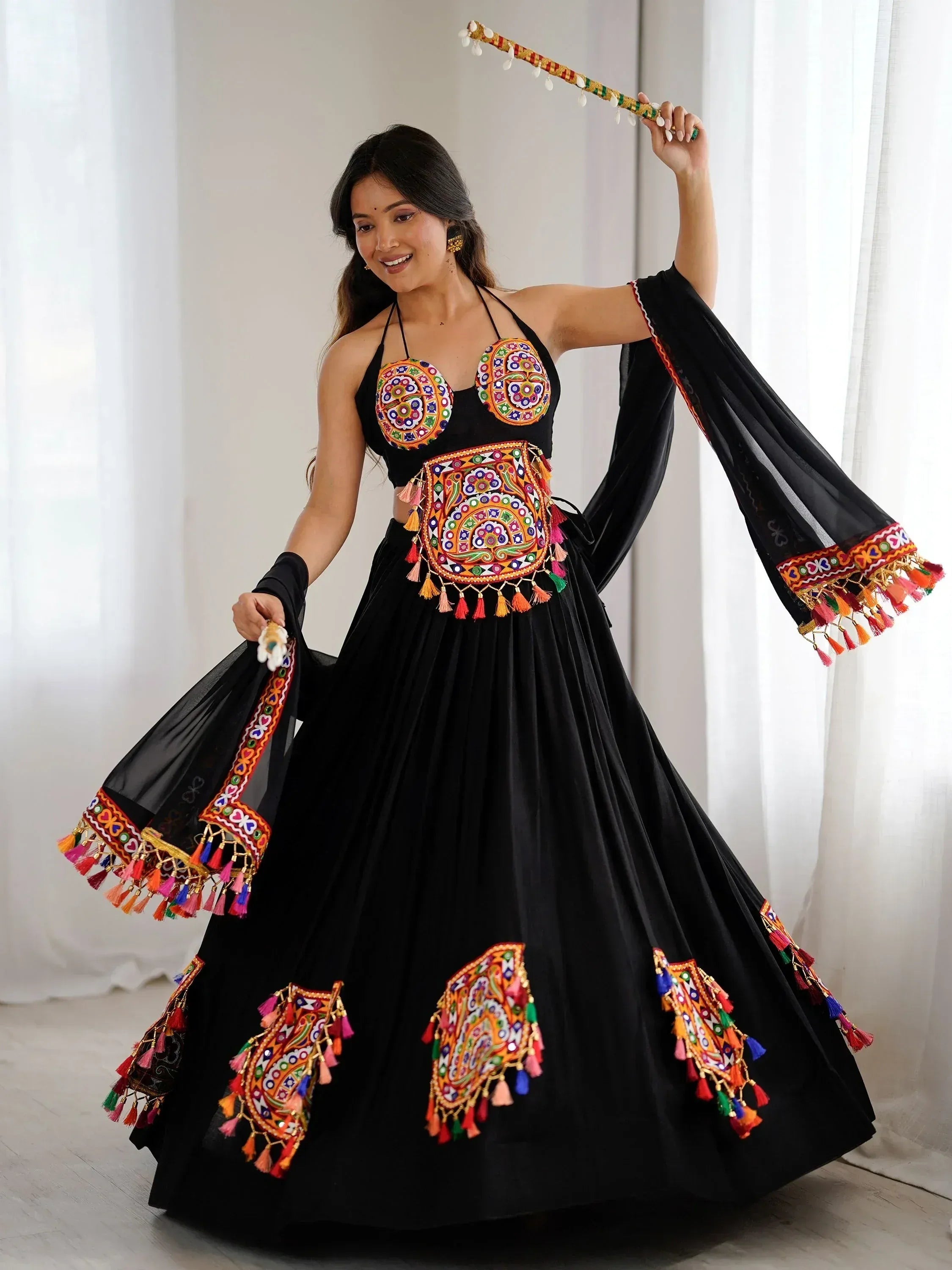 Black ethnic lehenga choli with colorful embroidery and tassels, perfect for festive occasions.