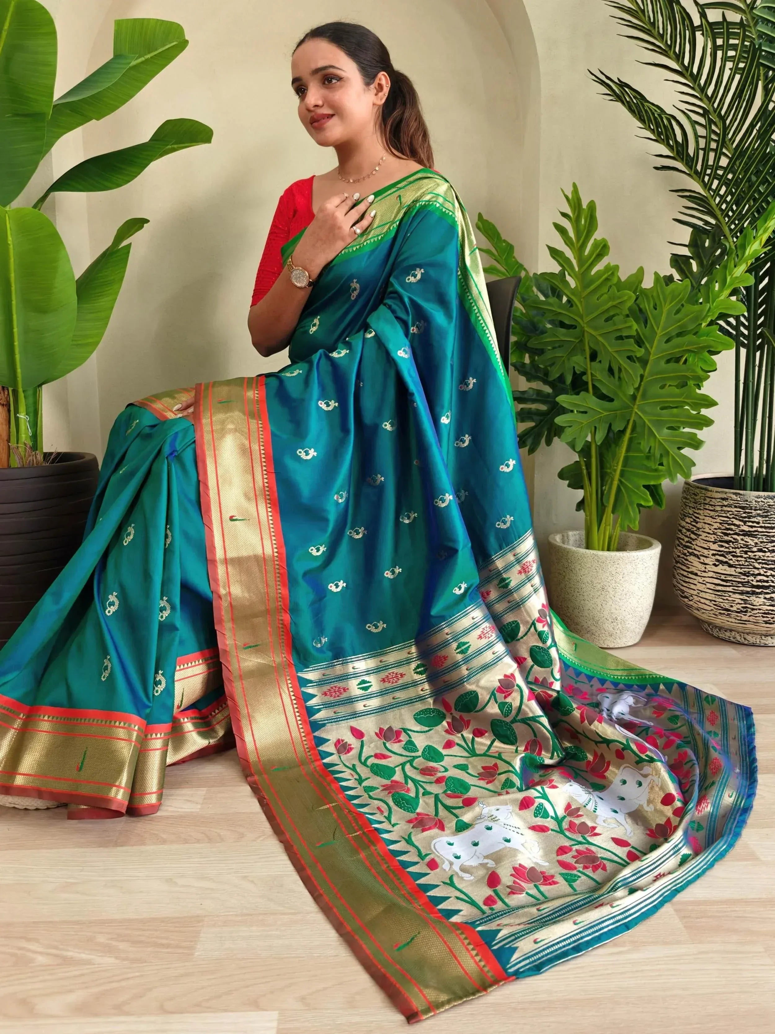 Teal silk saree with gold border, floral & elephant motifs, paired with red blouse, ideal for Indian ethnic occasions