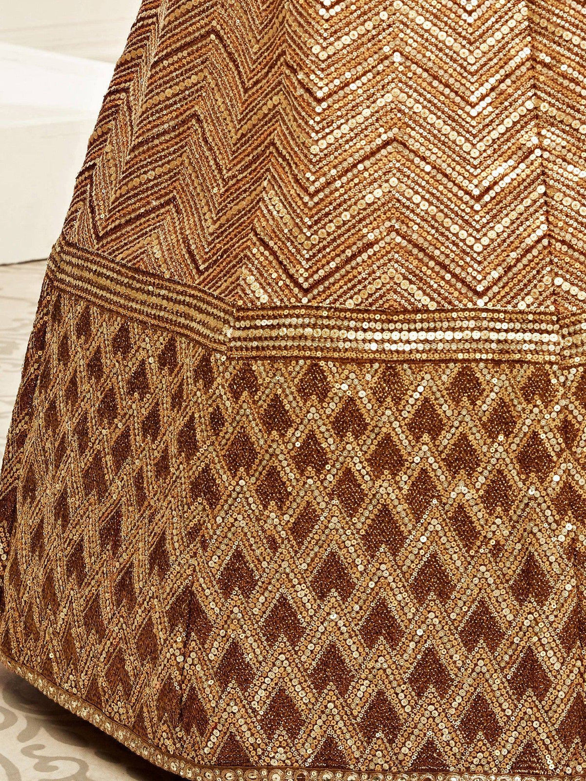 Close-up of gold sequin embroidery on a designer ethnic lehenga with geometric patterns.