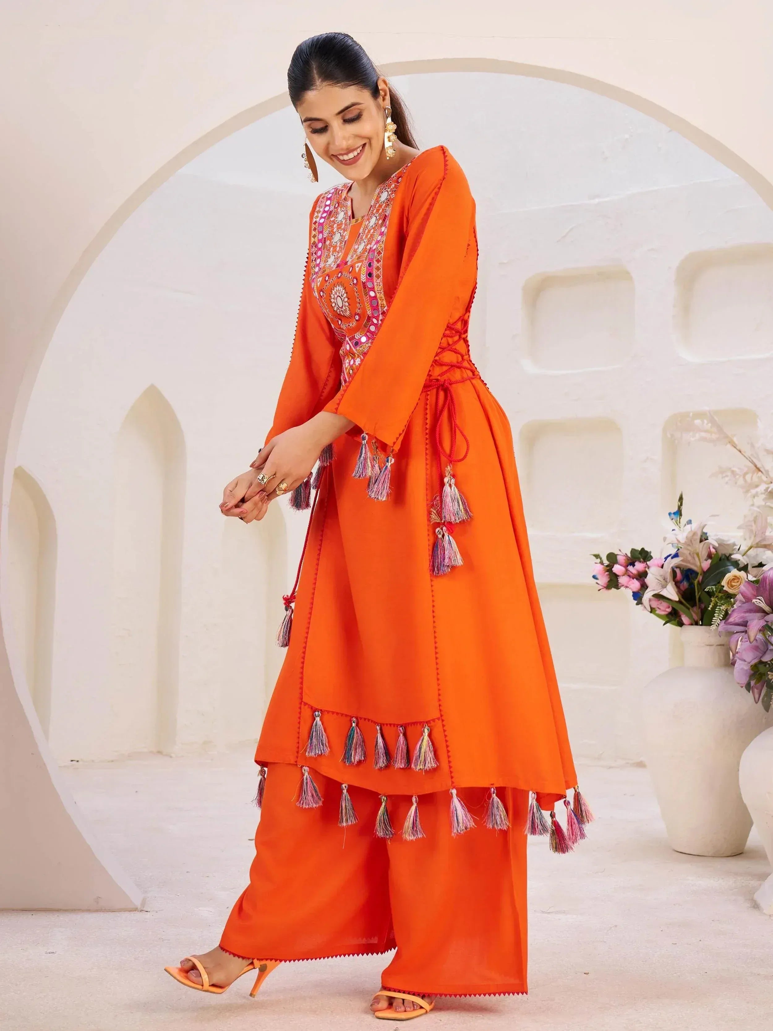 Vibrant orange ethnic anarkali suit with mirror work and tassels, perfect for Indian festive occasions