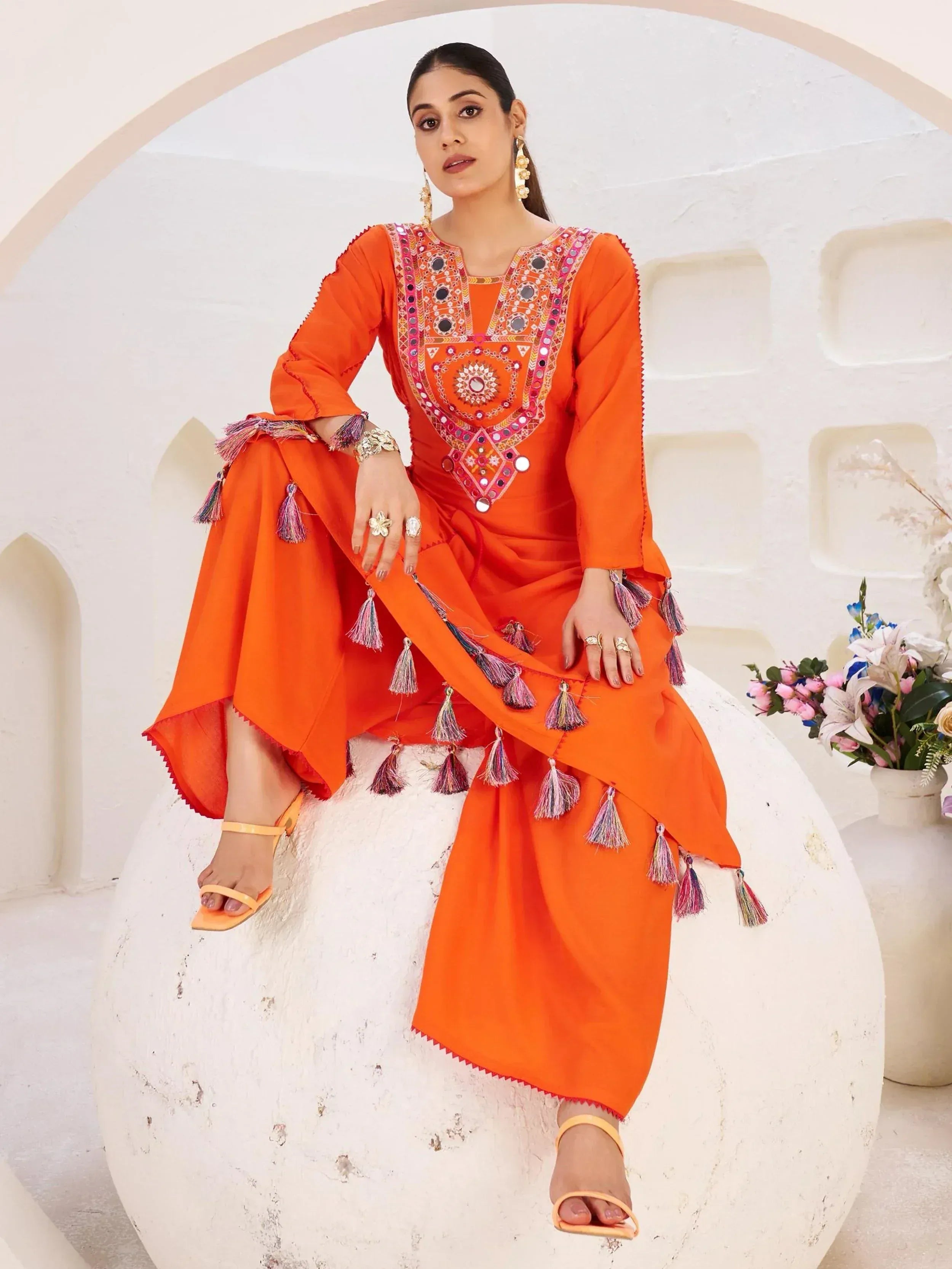 Orange ethnic salwar kameez with mirror work and tassels, perfect for festive occasions