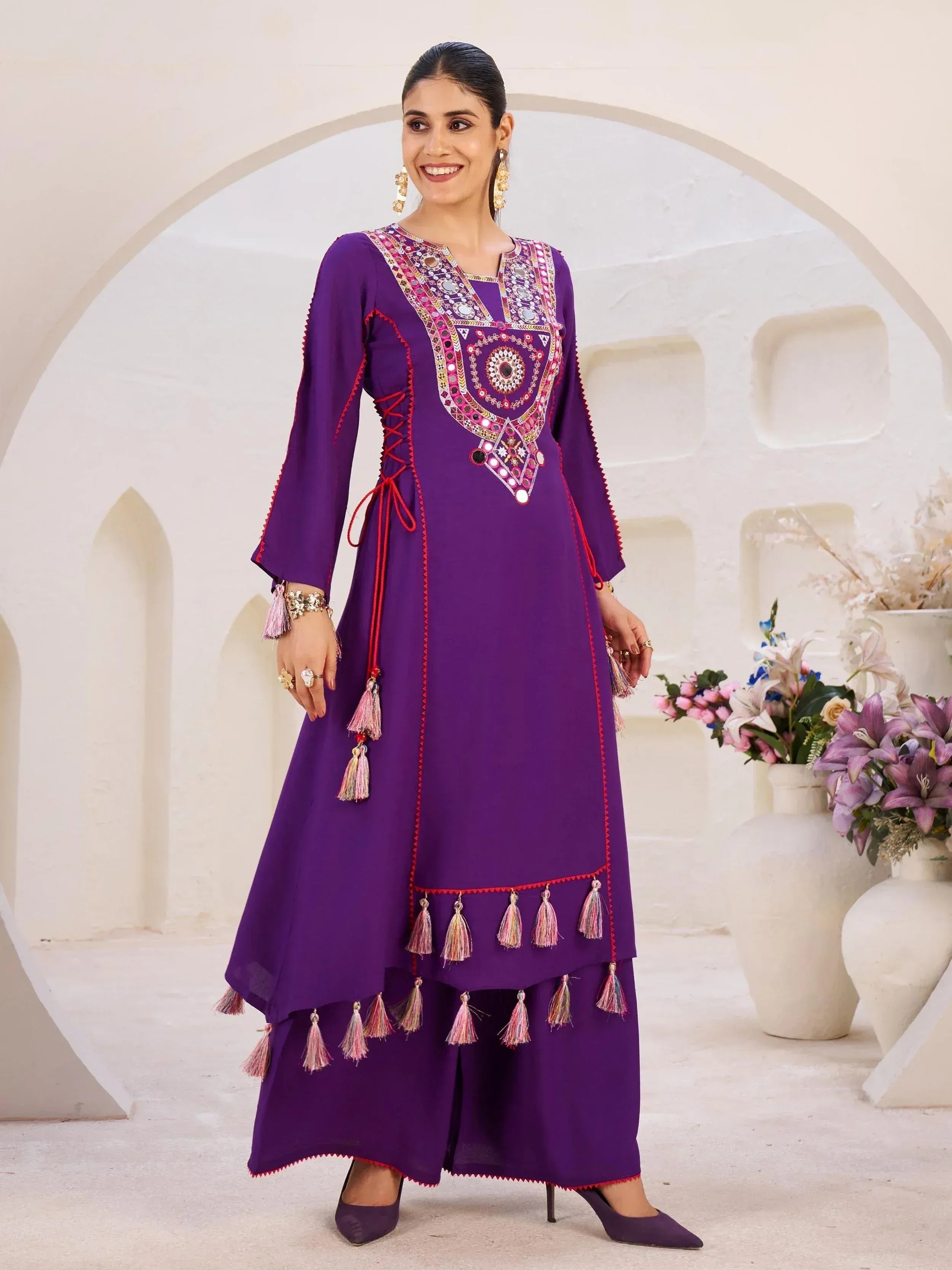 Purple ethnic kurta with mirror work and tassels, paired with palazzo pants for festive occasions