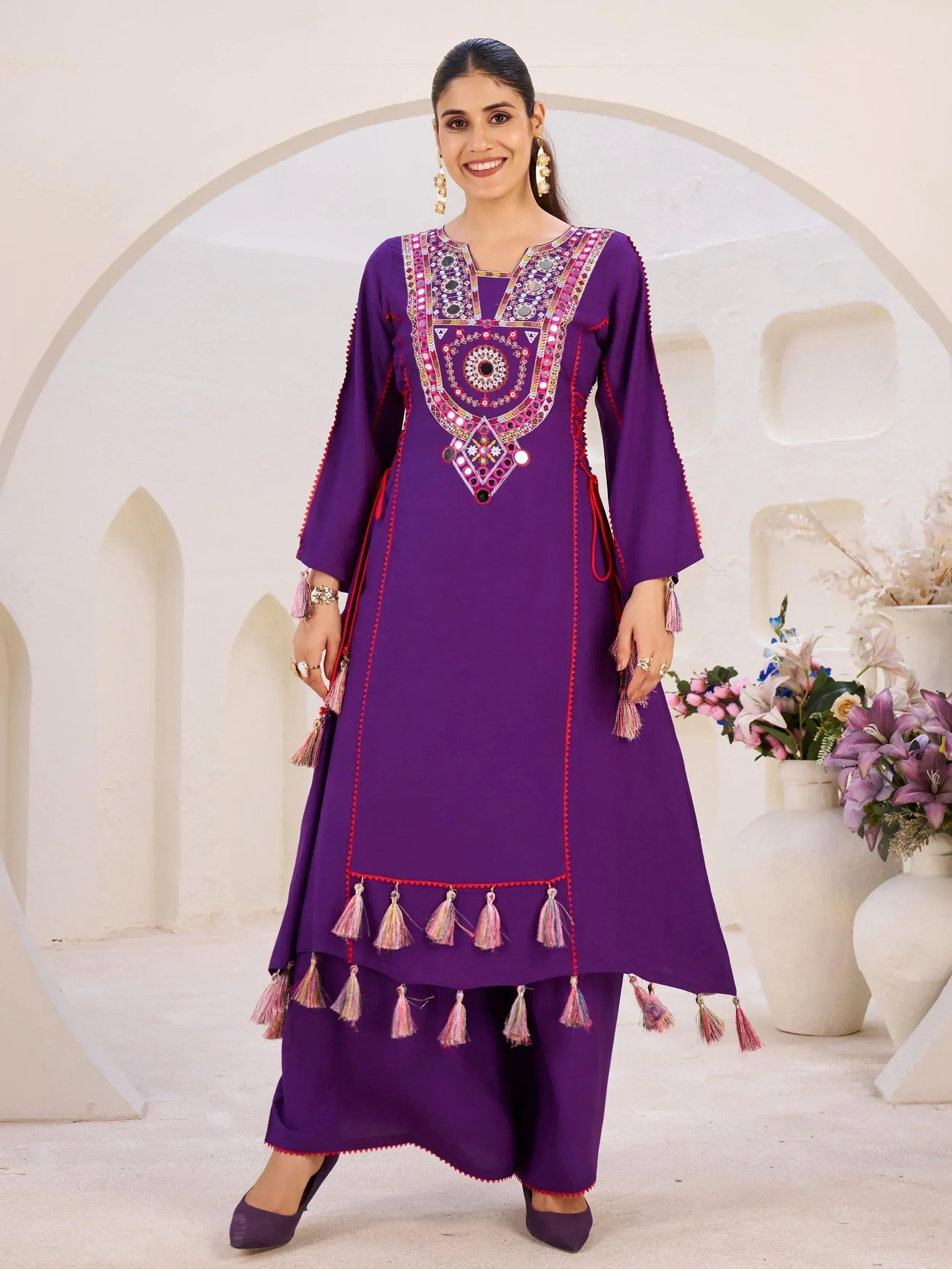 Purple ethnic kurti with mirror work and tassels, paired with palazzo pants for festive occasions