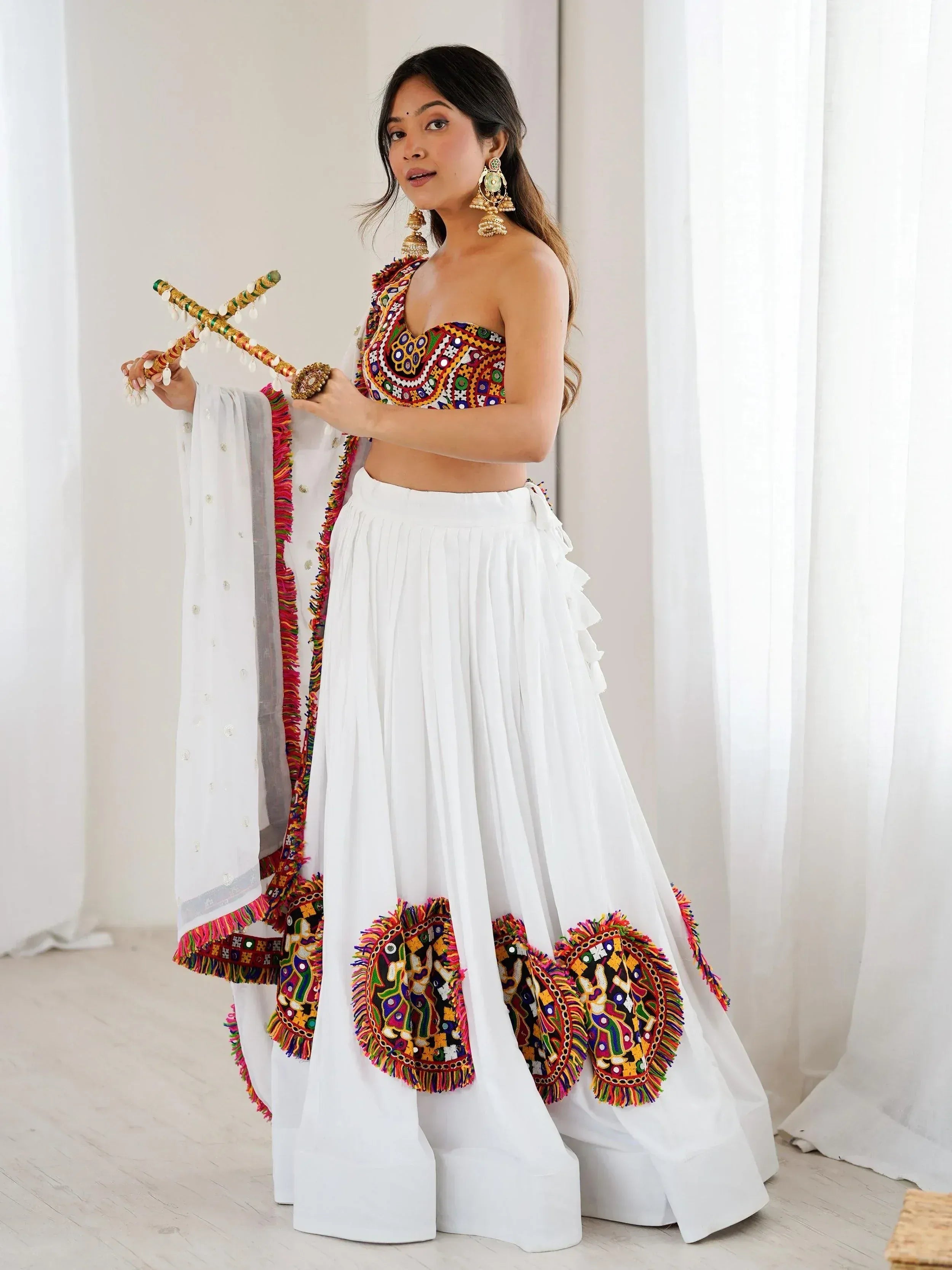 White ethnic lehenga with colorful mirror work, paired with embroidered blouse and dupatta, perfect for Indian celebrations.