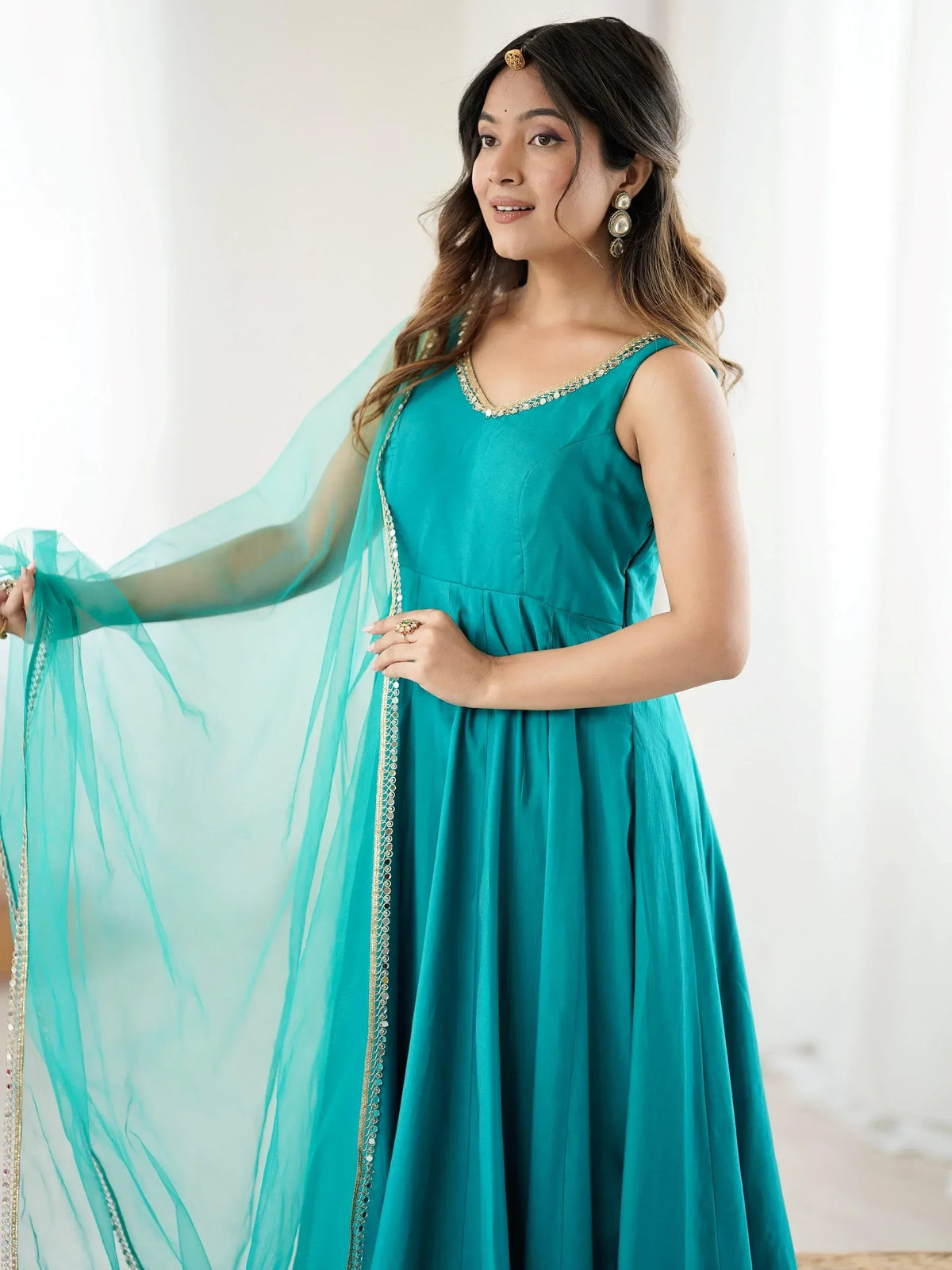 Teal ethnic gown with gold trim and sheer dupatta, perfect for Indian festive occasions