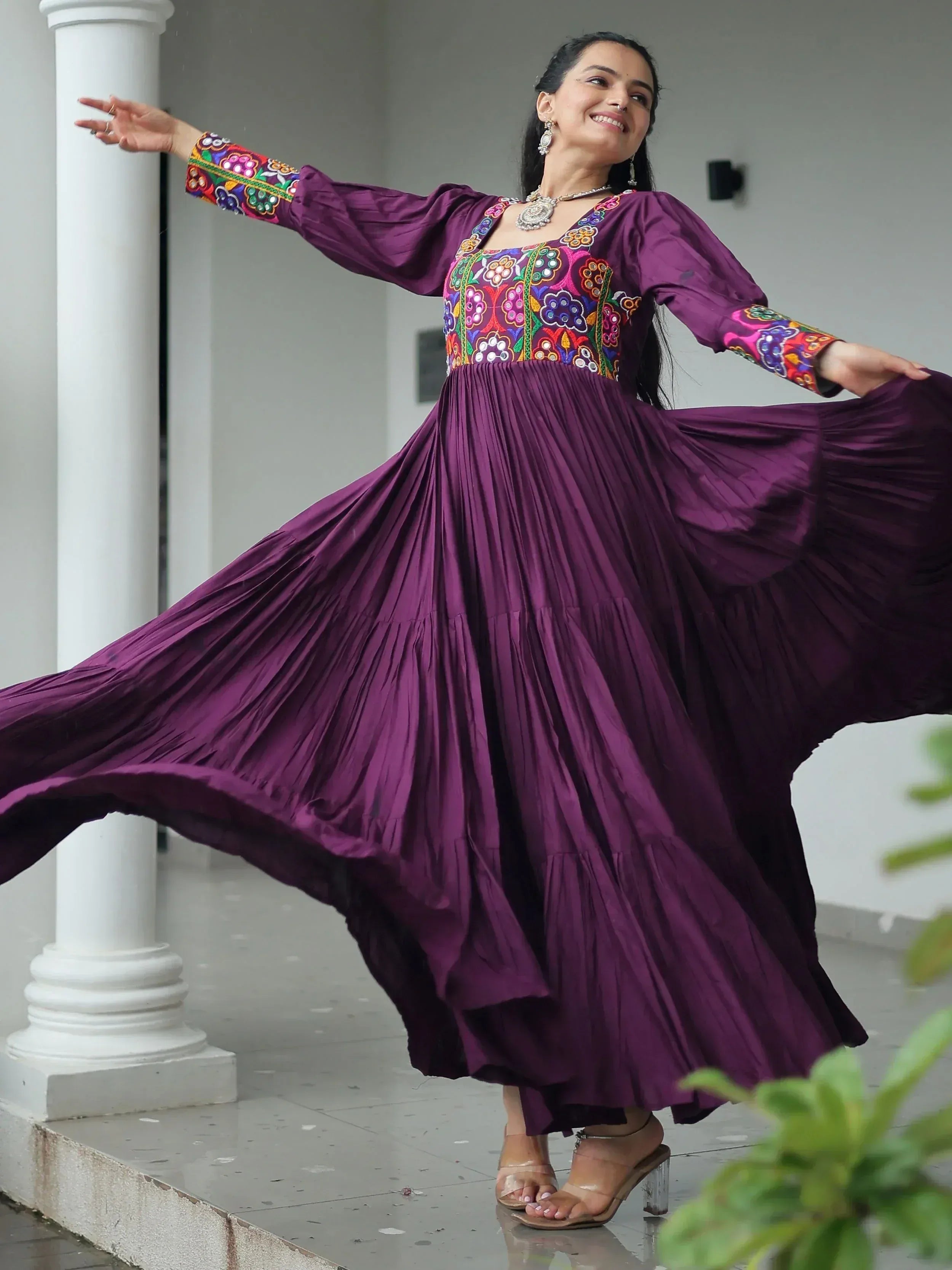 Woman twirling in purple ethnic gown with colorful embroidery, perfect for Indian festive occasions.