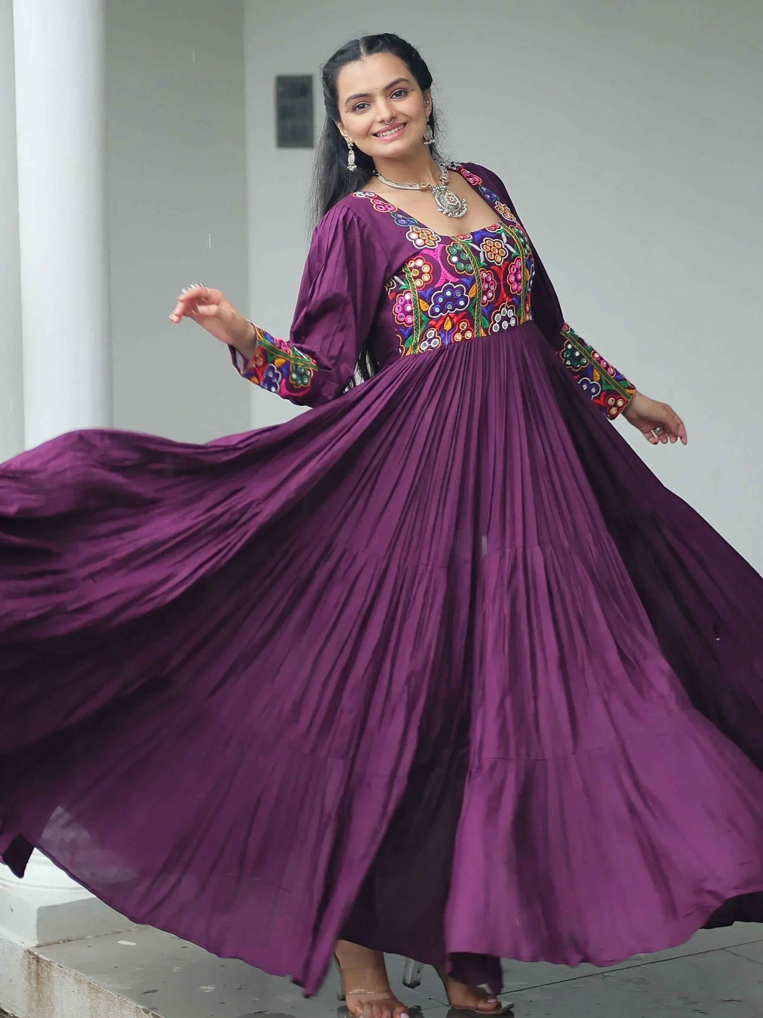Purple ethnic gown with colorful floral embroidery, pleated skirt, and long sleeves for women