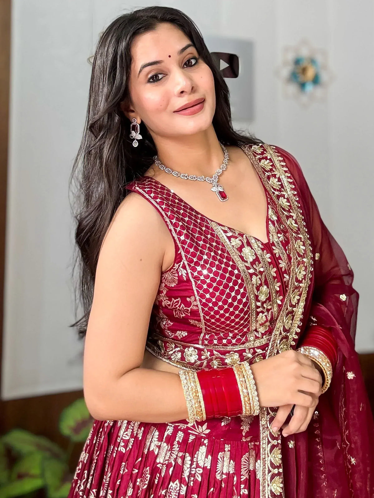 Woman in maroon embroidered lehenga choli with gold detailing, perfect for Indian ethnic wear occasions.