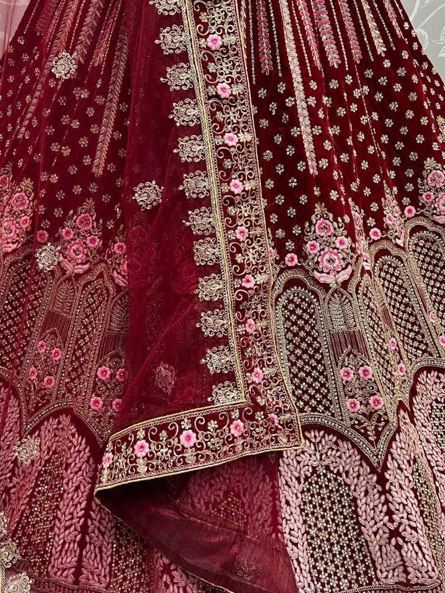 Maroon velvet lehenga with gold and pink floral embroidery, perfect for Indian weddings and festive occasions.
