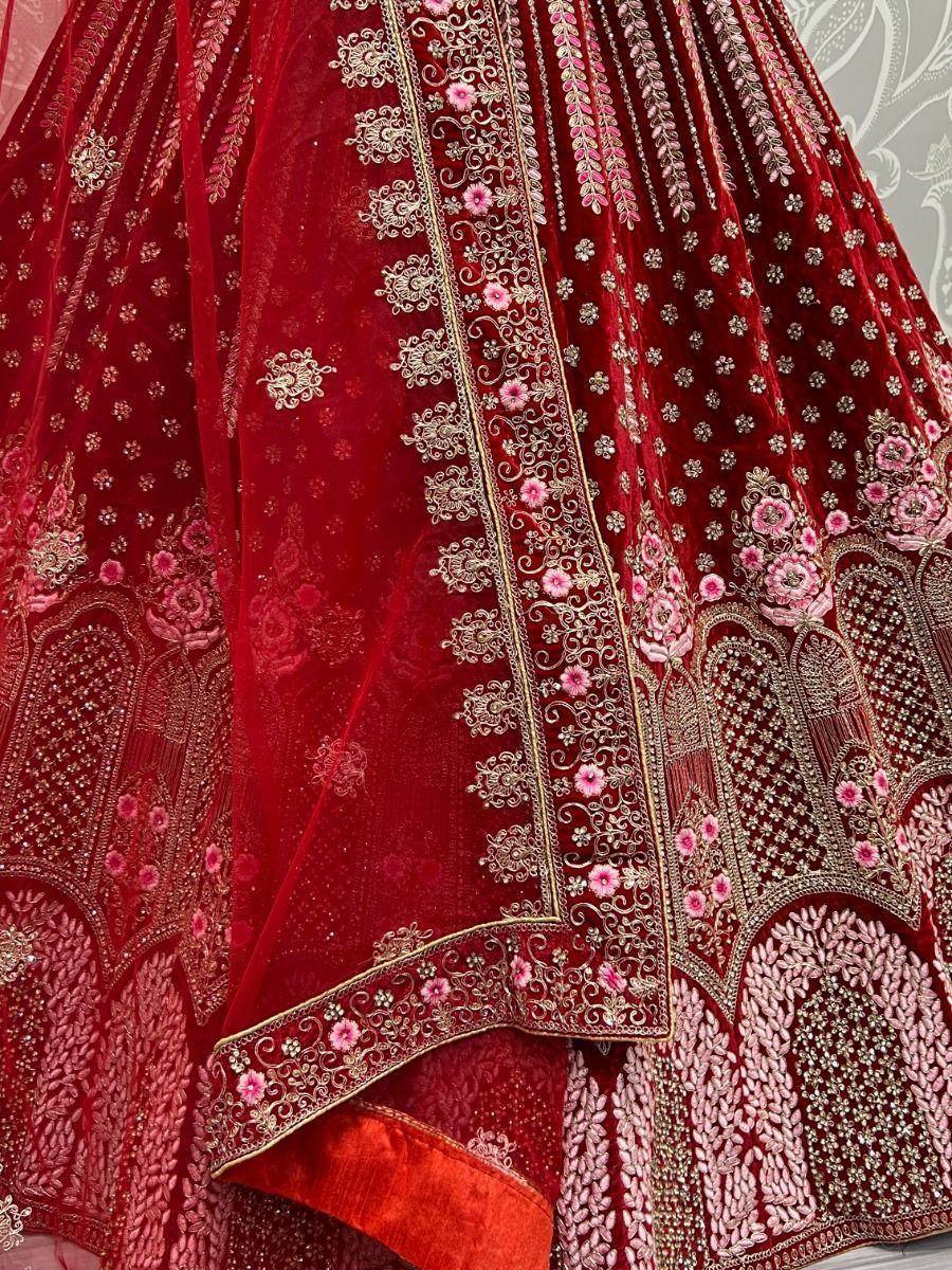 Red velvet lehenga choli with pink floral embroidery and gold detailing, perfect for Indian weddings.