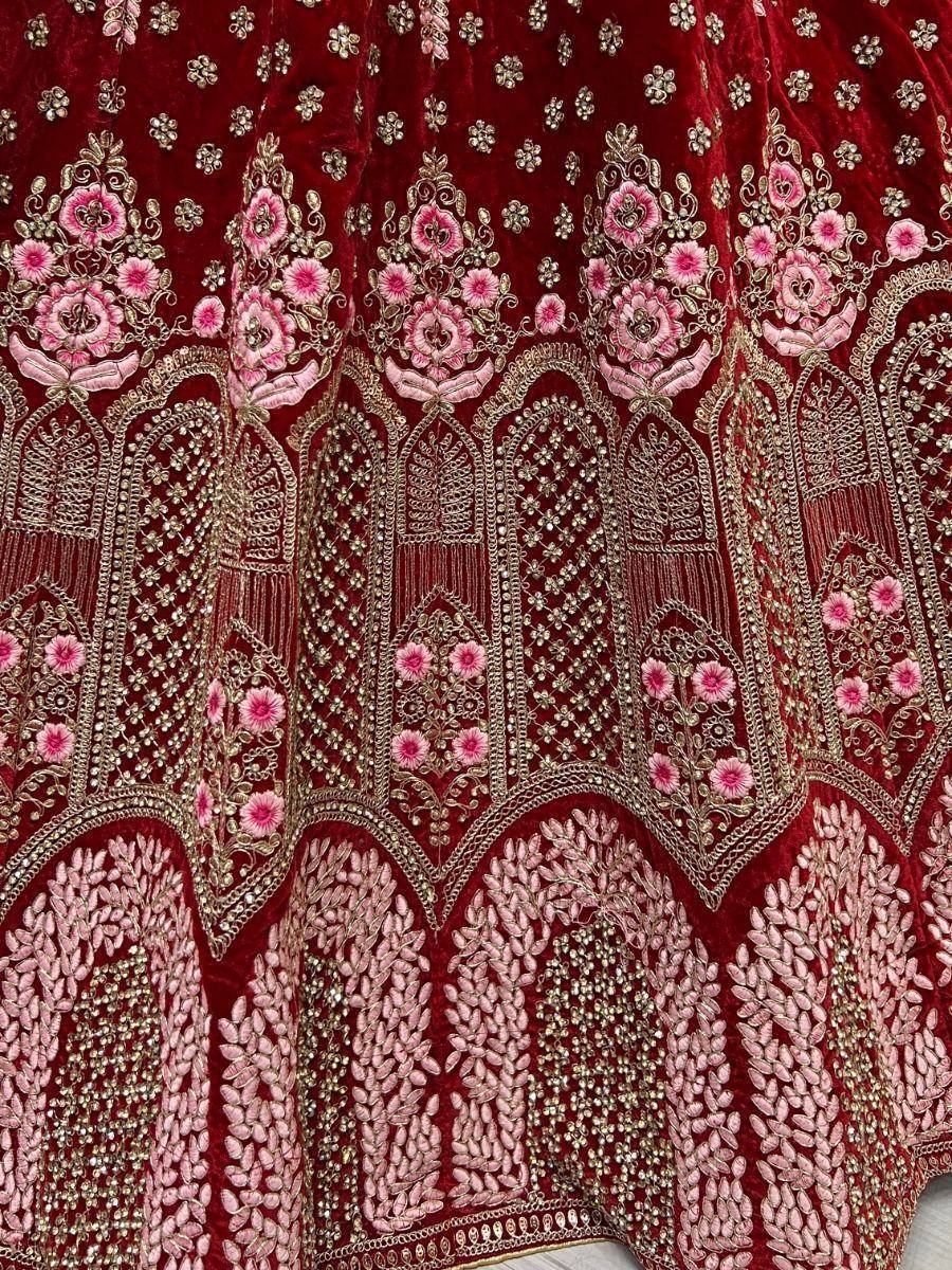 Rich maroon velvet lehenga with pink floral embroidery and gold zari work, perfect for Indian weddings