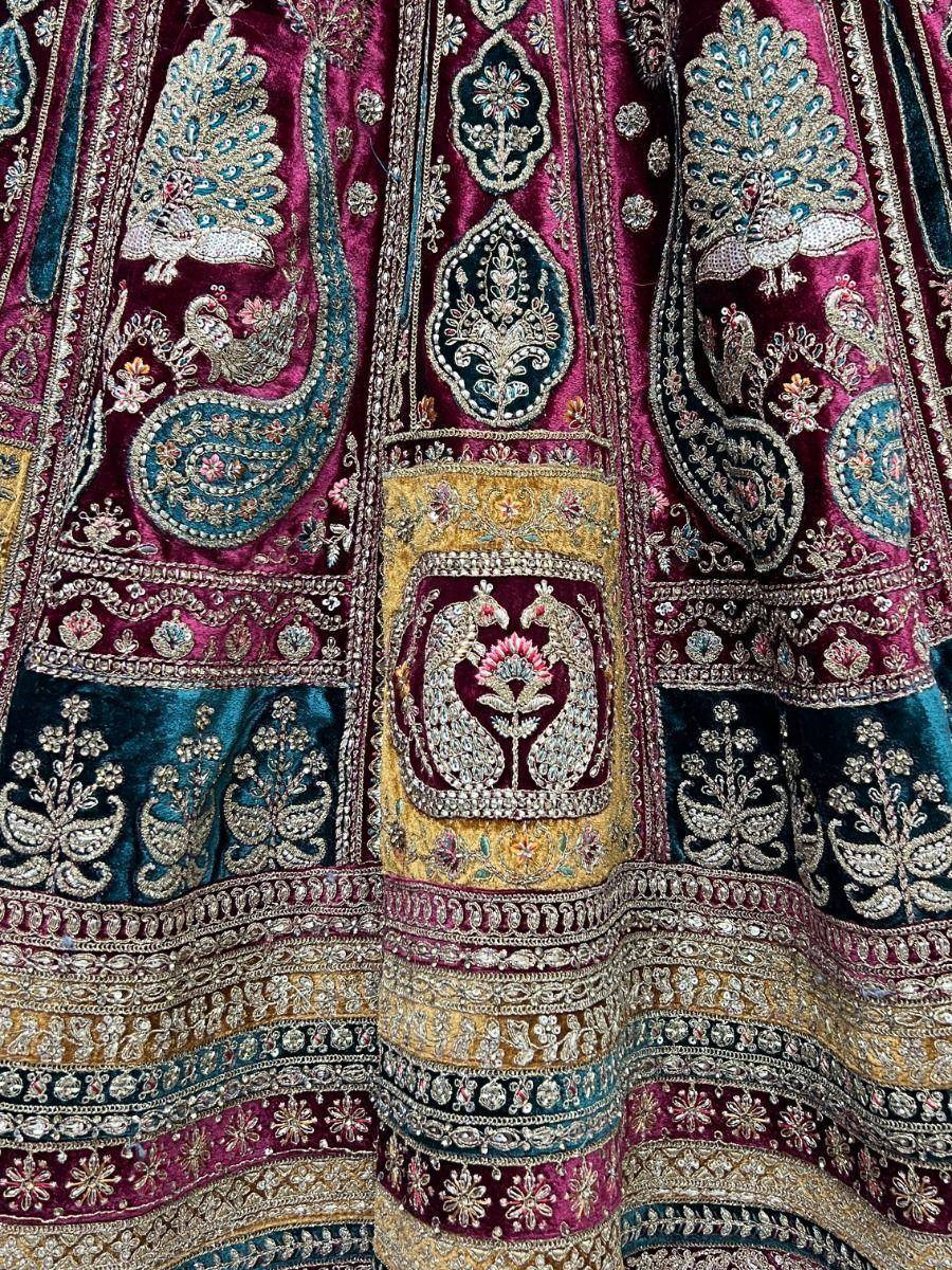 Luxury Indian lehenga with peacock embroidery, velvet fabric, and intricate zari work in maroon and teal.