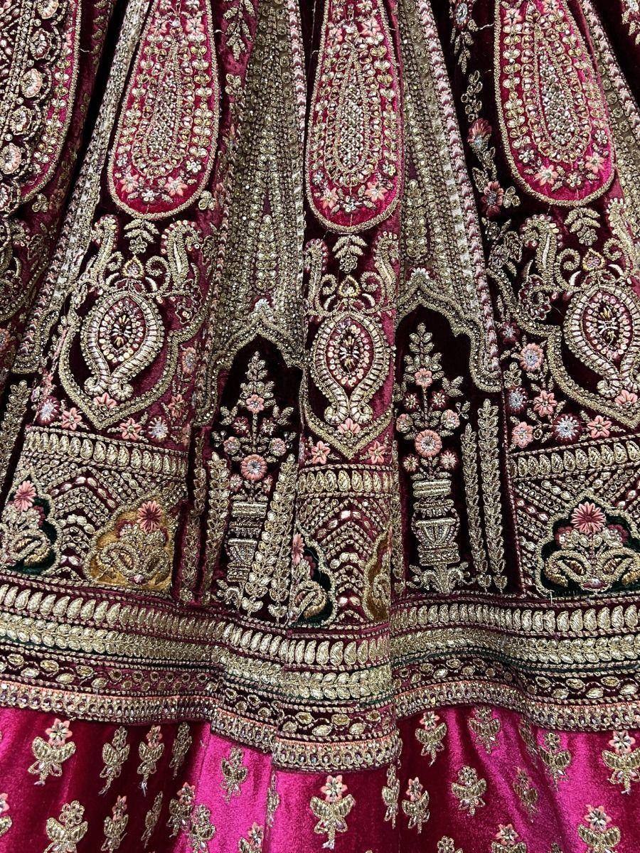 Luxury maroon velvet lehenga with intricate gold embroidery and floral motifs, perfect for Indian weddings.