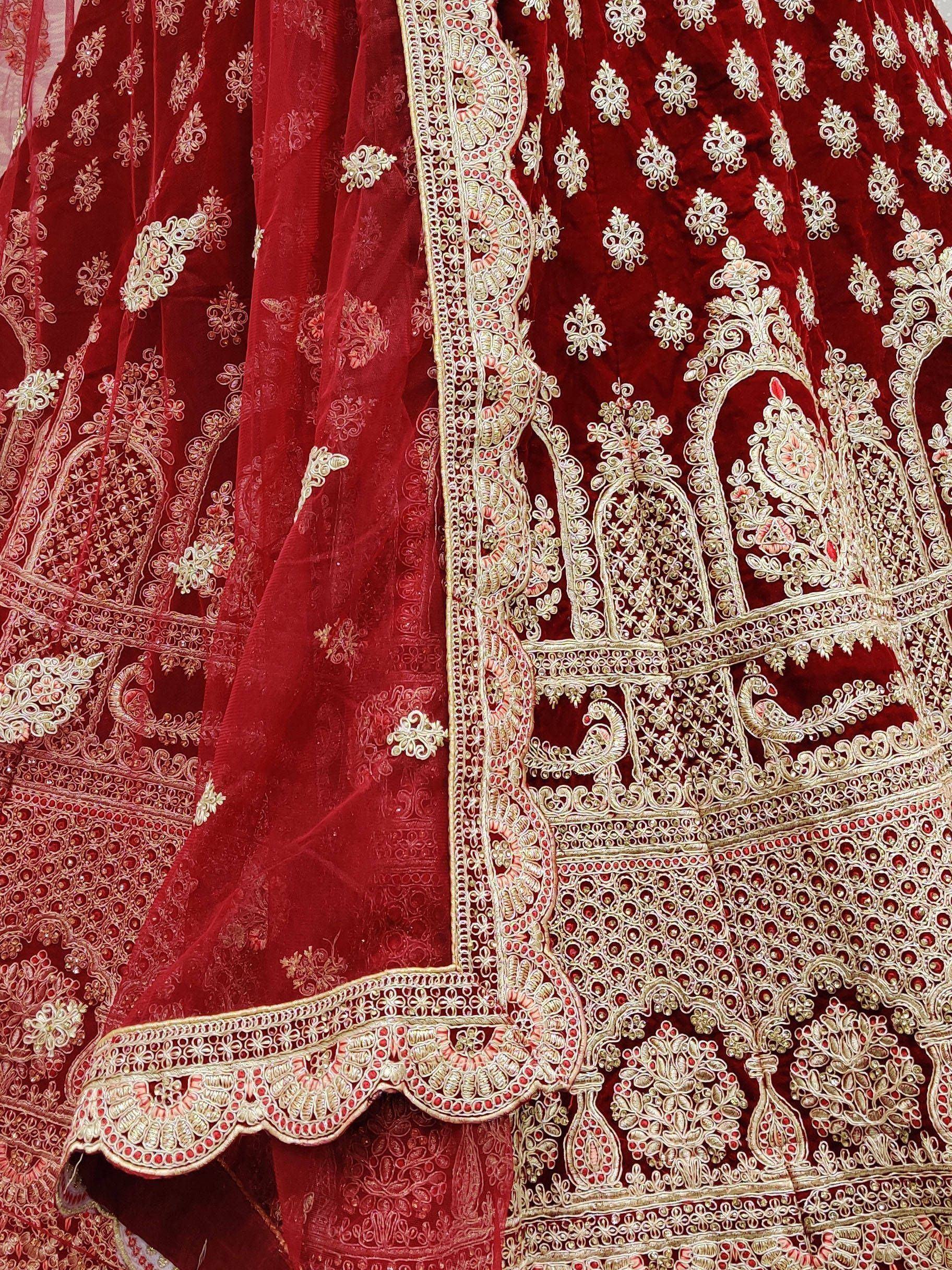Red velvet lehenga choli with intricate gold embroidery and peacock motifs, perfect for Indian weddings.