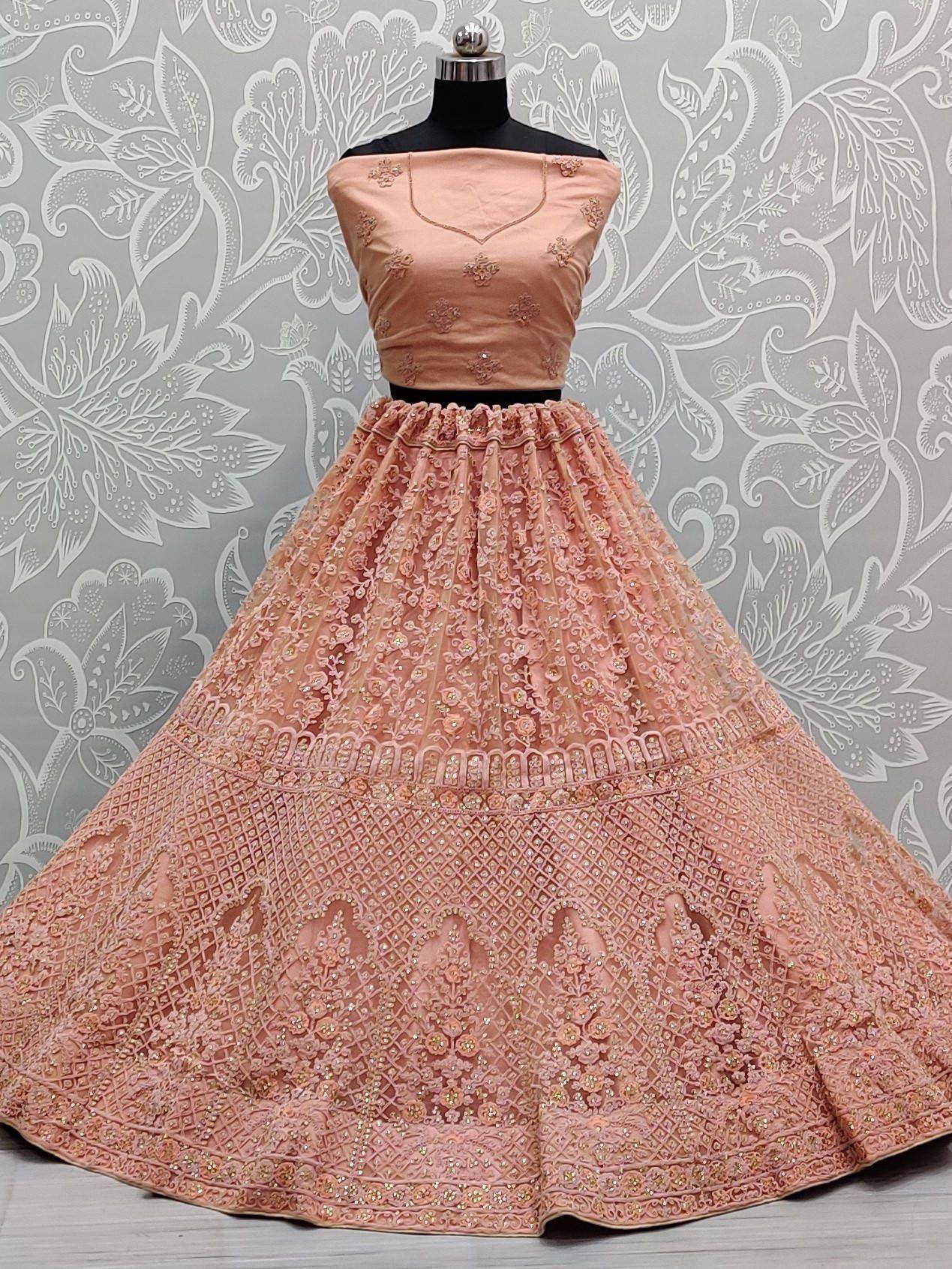 Peach designer lehenga choli with intricate embroidery and net skirt, perfect for Indian ethnic wear occasions.
