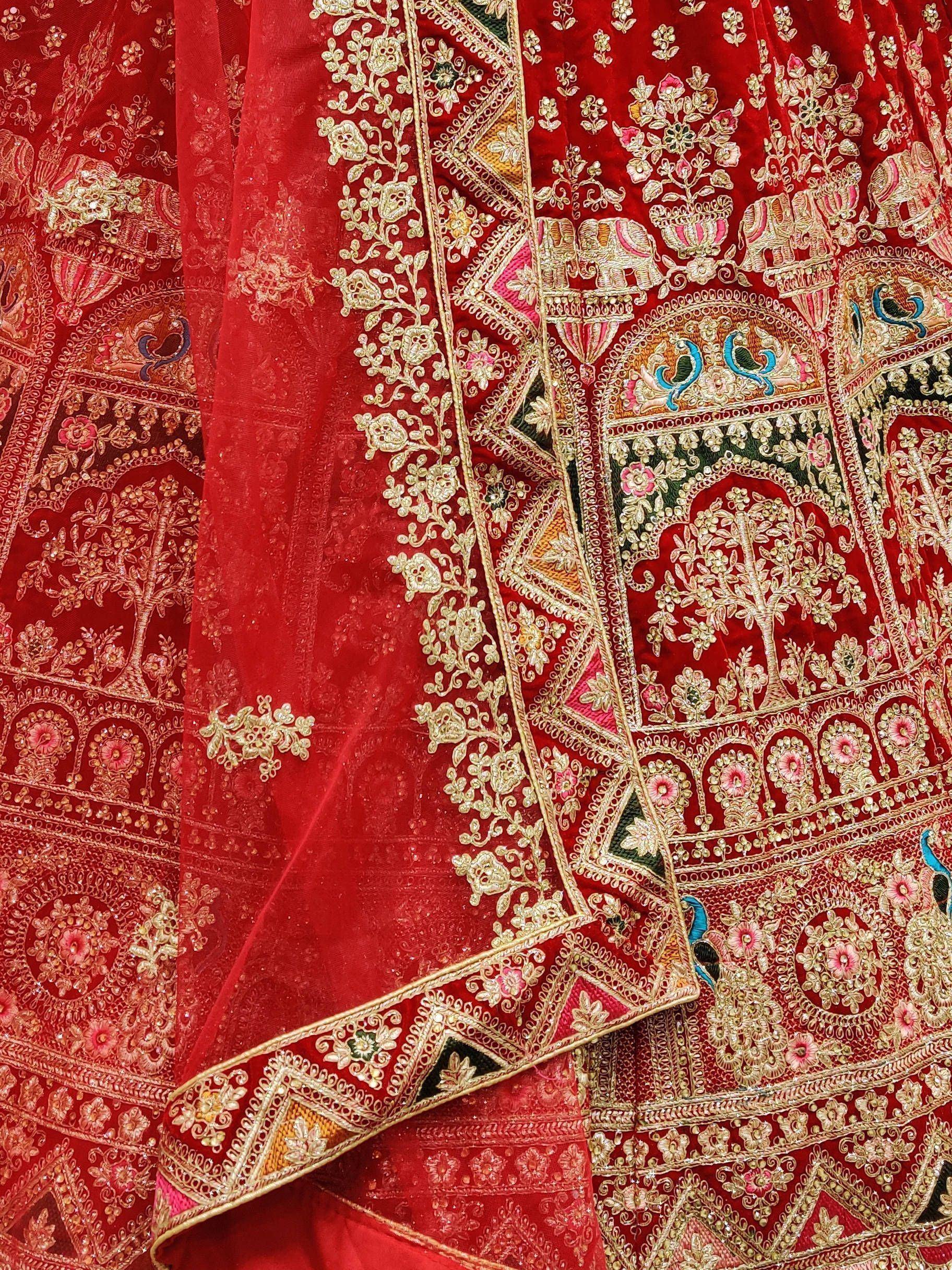 Red velvet lehenga with gold embroidery, floral and elephant motifs, perfect for Indian weddings and festivals.
