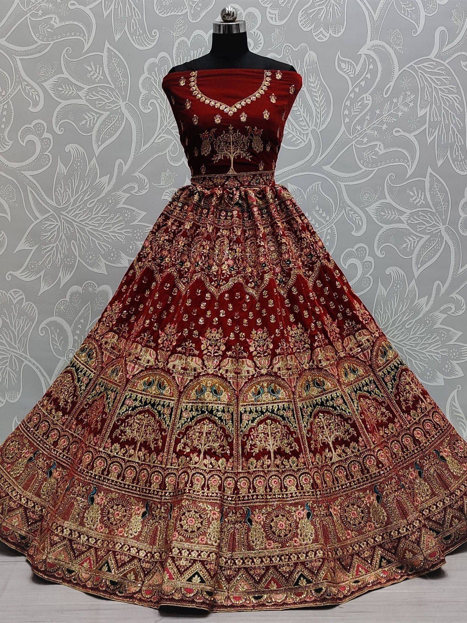 Maroon velvet lehenga choli with heavy gold embroidery, perfect for Indian weddings and festive occasions.