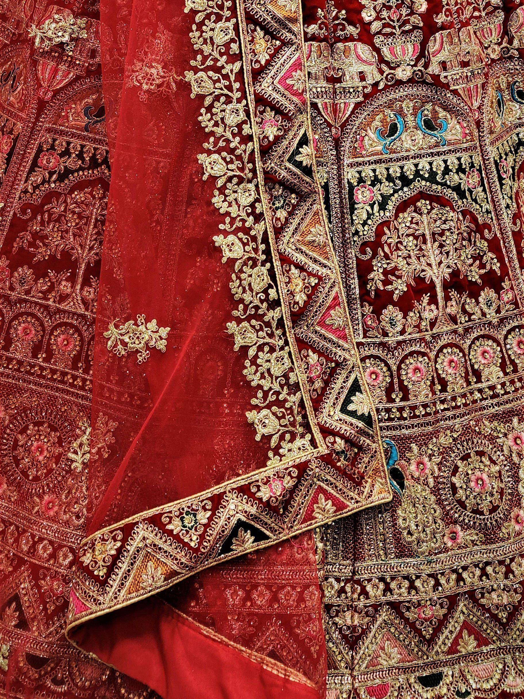 Luxury red velvet lehenga with intricate gold embroidery, peacock, and elephant motifs for Indian weddings