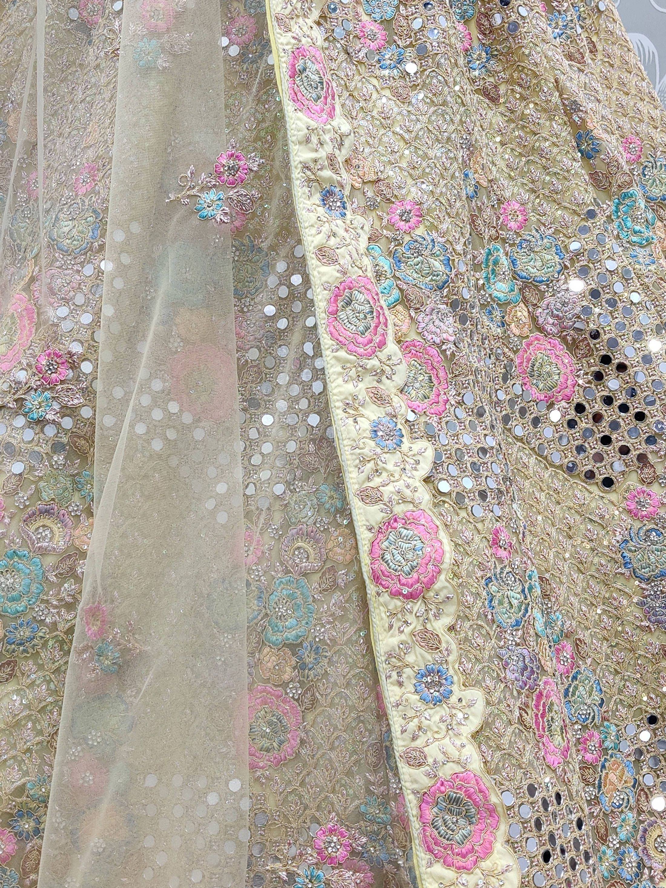 Gold ethnic lehenga with pink and blue floral embroidery and mirror work detail
