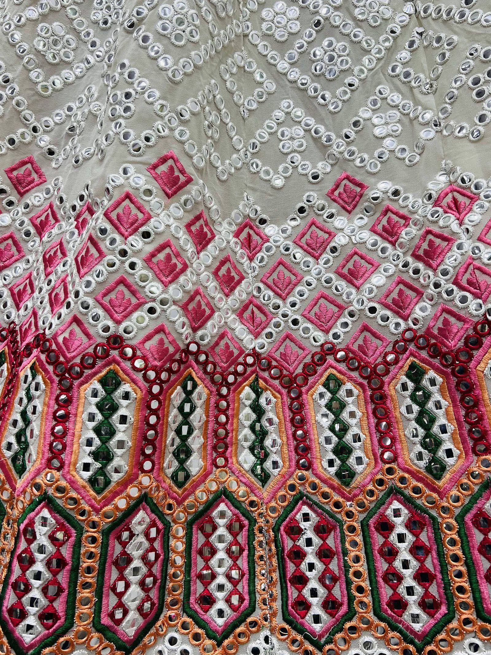 Indian ethnic wear with intricate mirror work and colorful embroidery on beige fabric