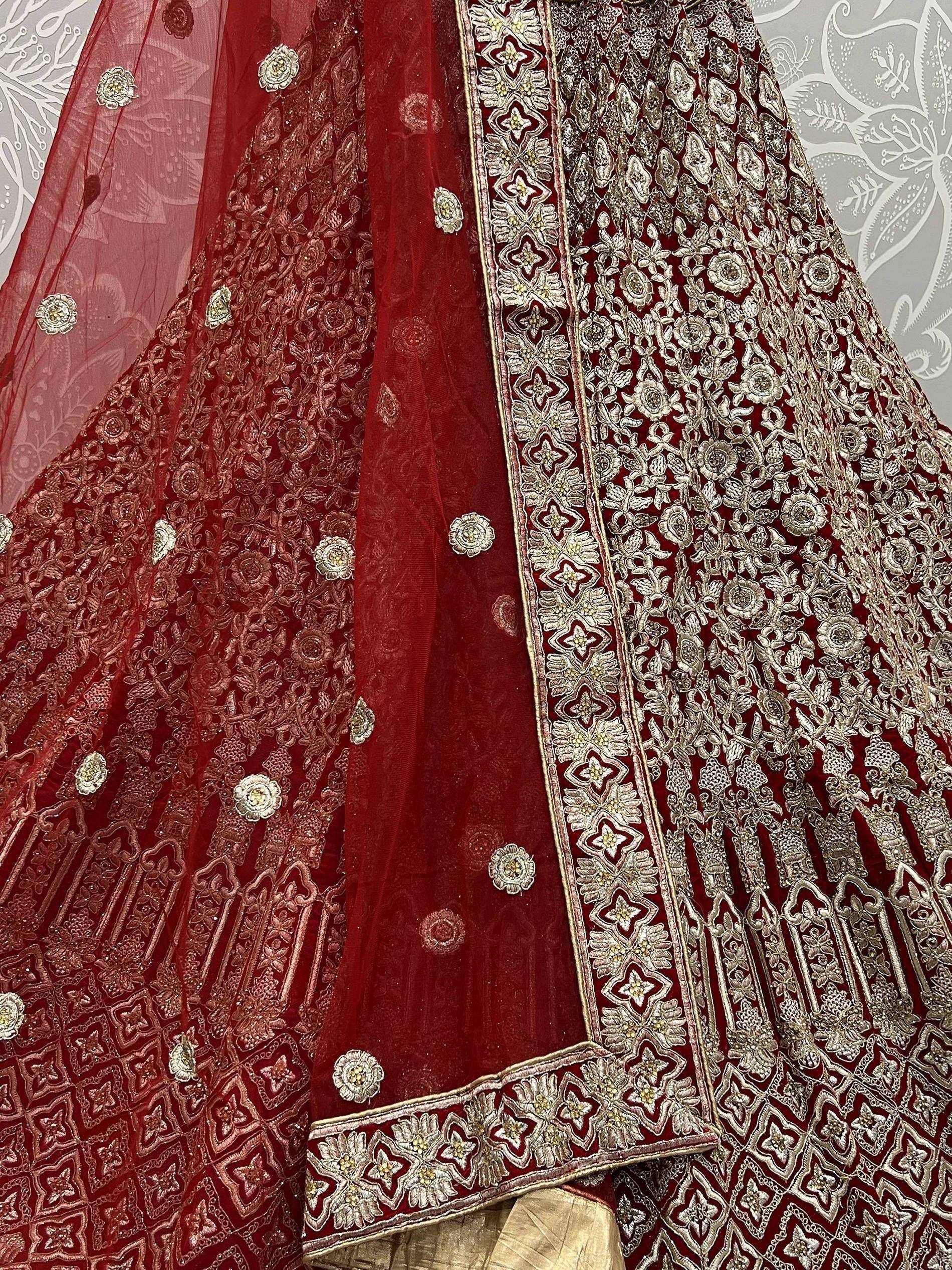 Rich maroon lehenga choli with intricate silver embroidery and floral motifs, perfect for Indian weddings.