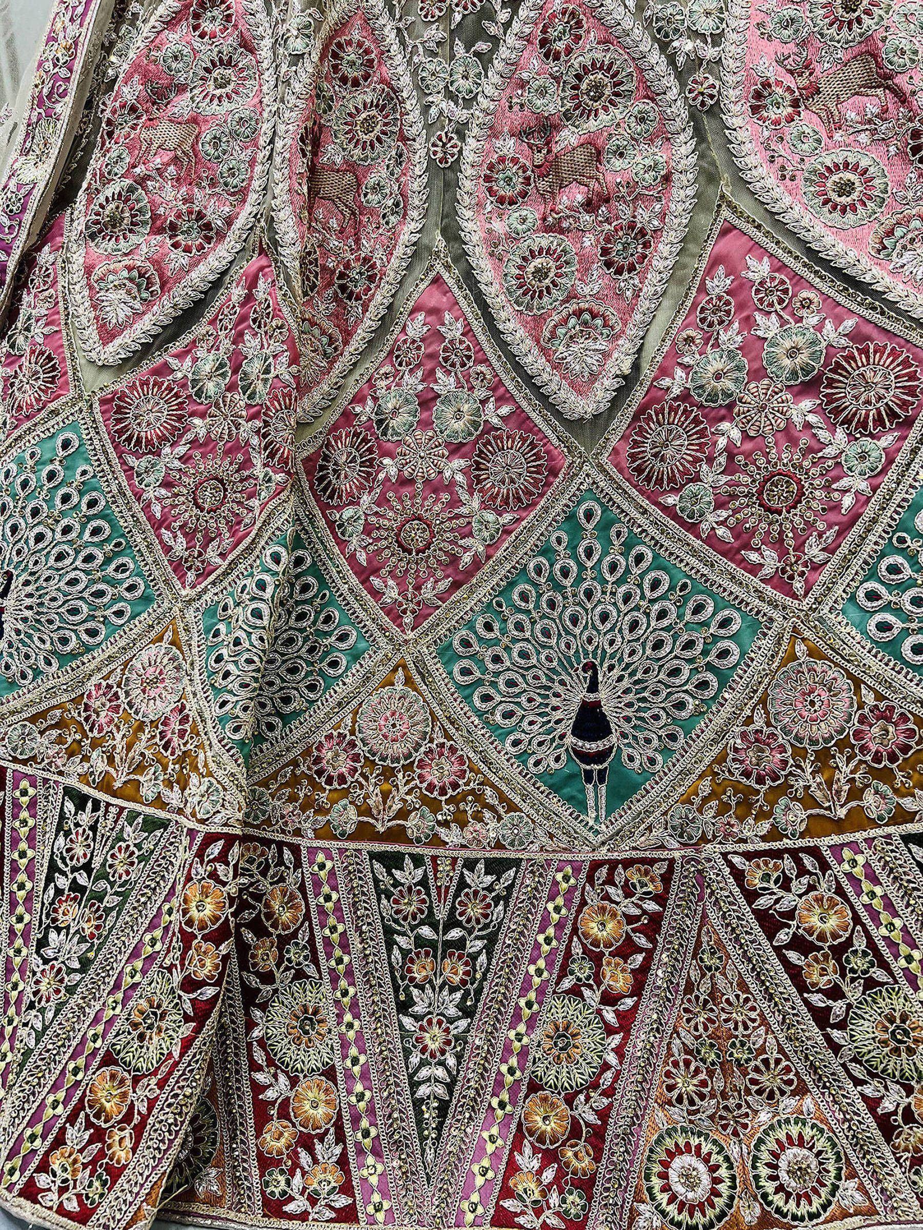 Indian ethnic lehenga with intricate floral and peacock embroidery in pink, green, and gold tones