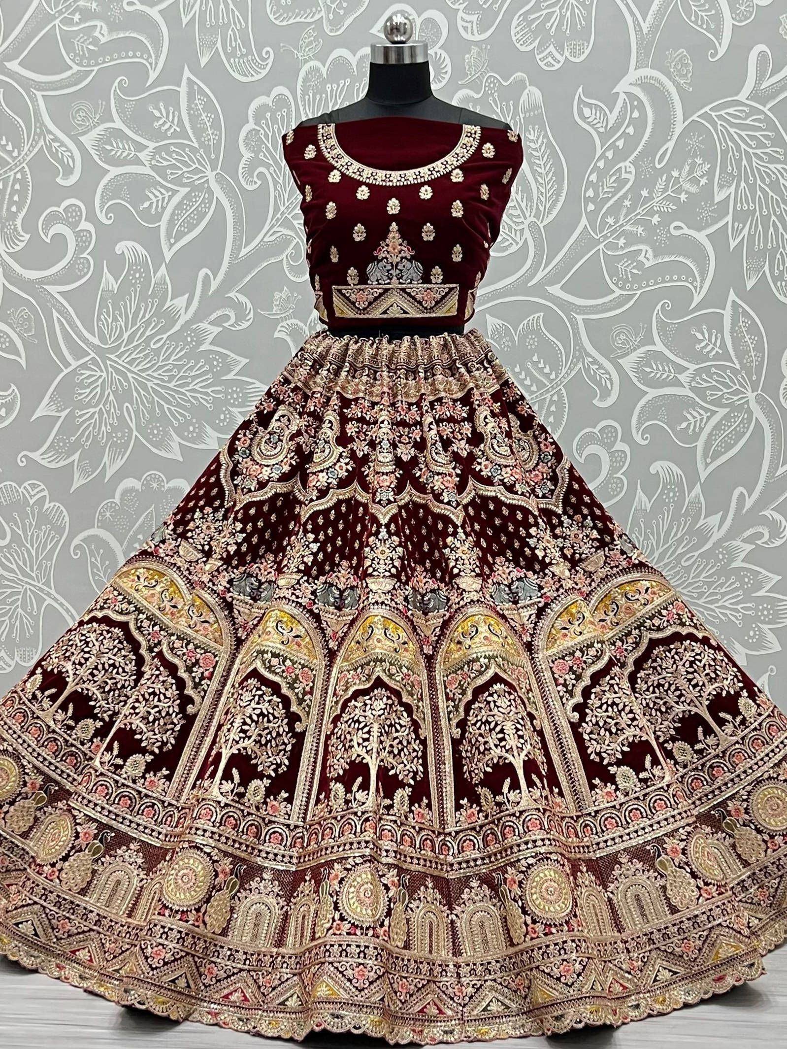 Maroon velvet designer lehenga choli with heavy gold embroidery and floral motifs, perfect for Indian weddings.