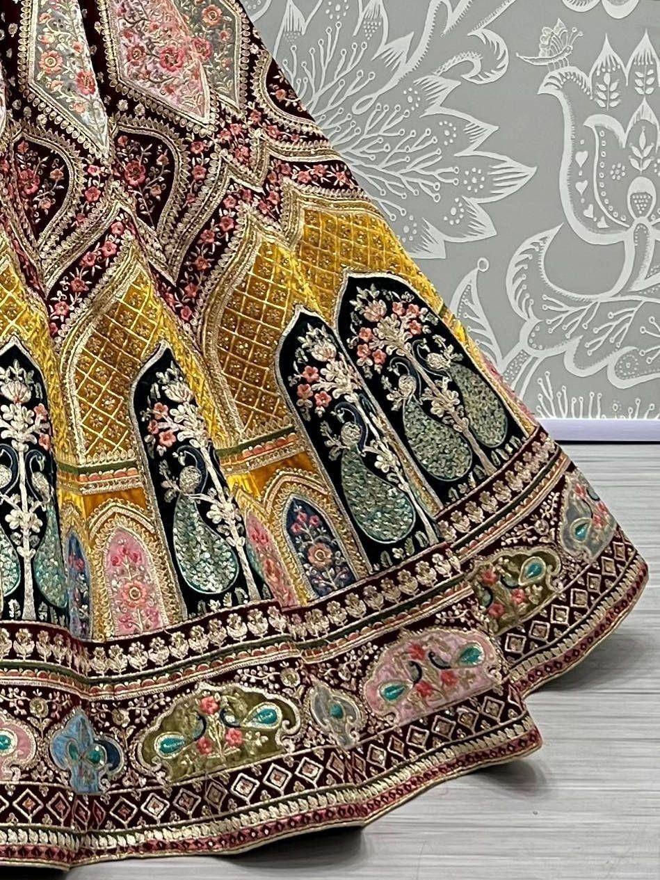 Designer lehenga with intricate peacock embroidery and floral motifs in maroon, gold, and teal