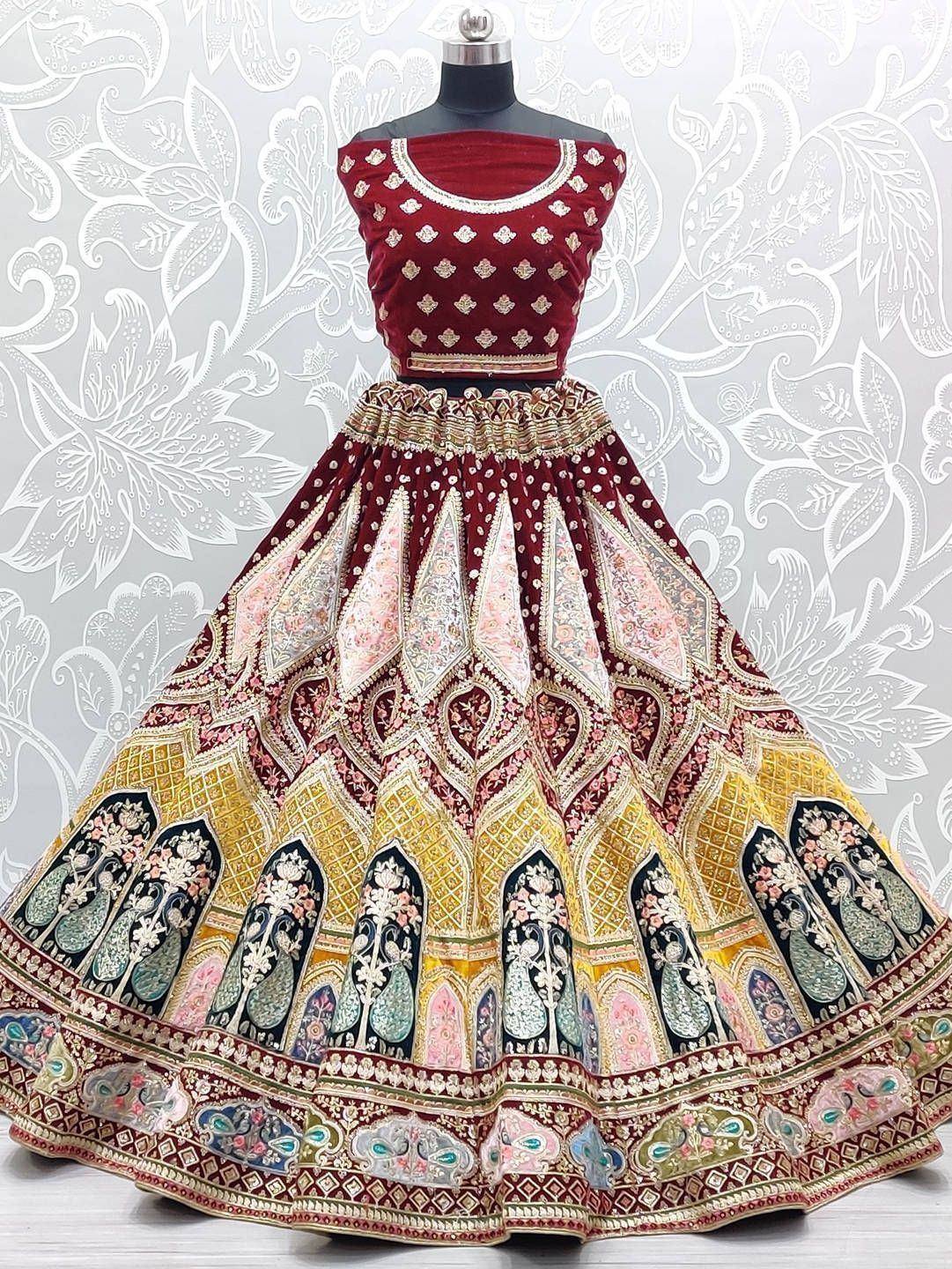 Maroon velvet lehenga choli with intricate gold and peacock embroidery, perfect for Indian weddings and festive occasions.