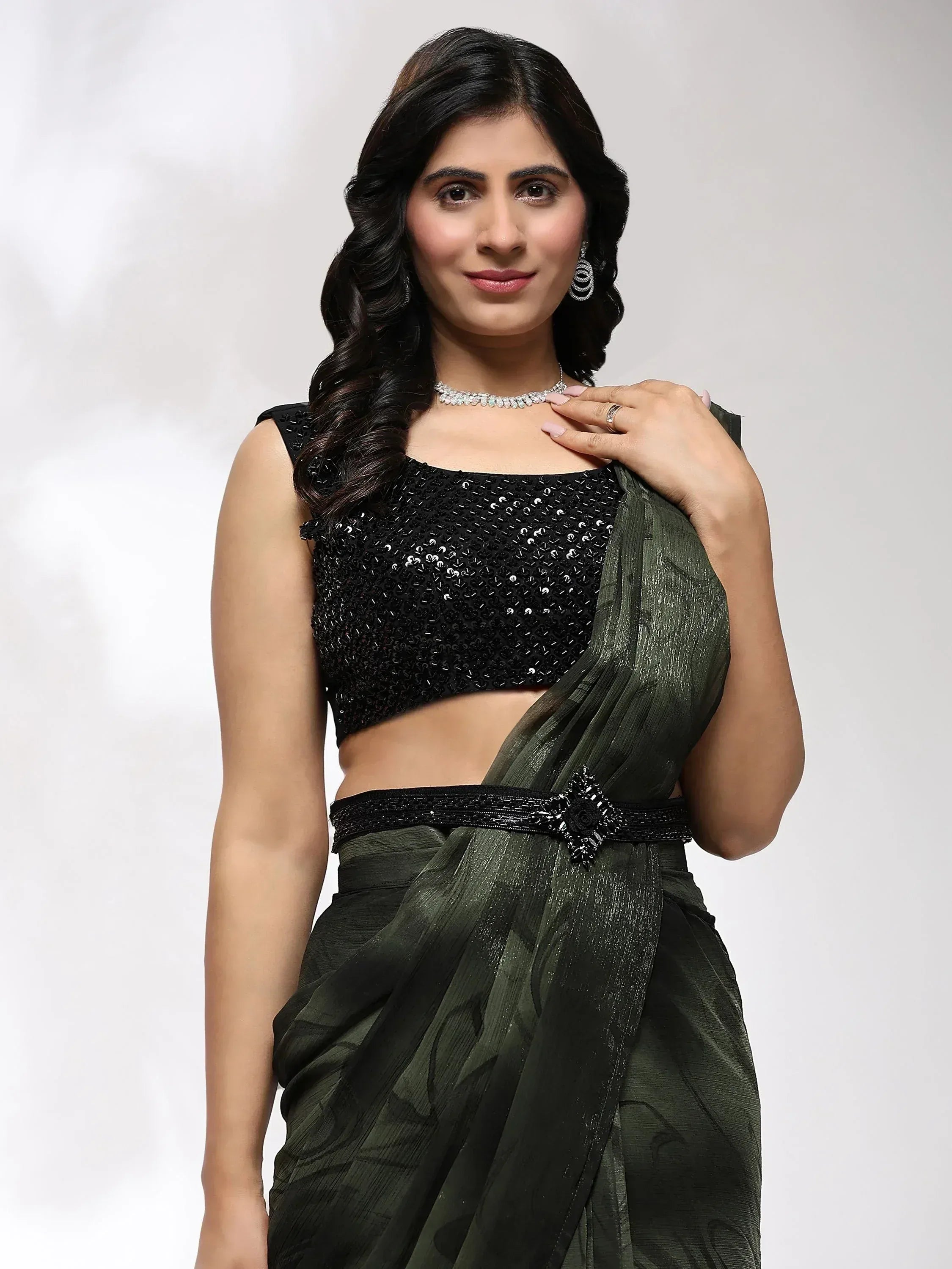 Woman in olive green saree with black sequin blouse, elegant ethnic wear for festive occasions