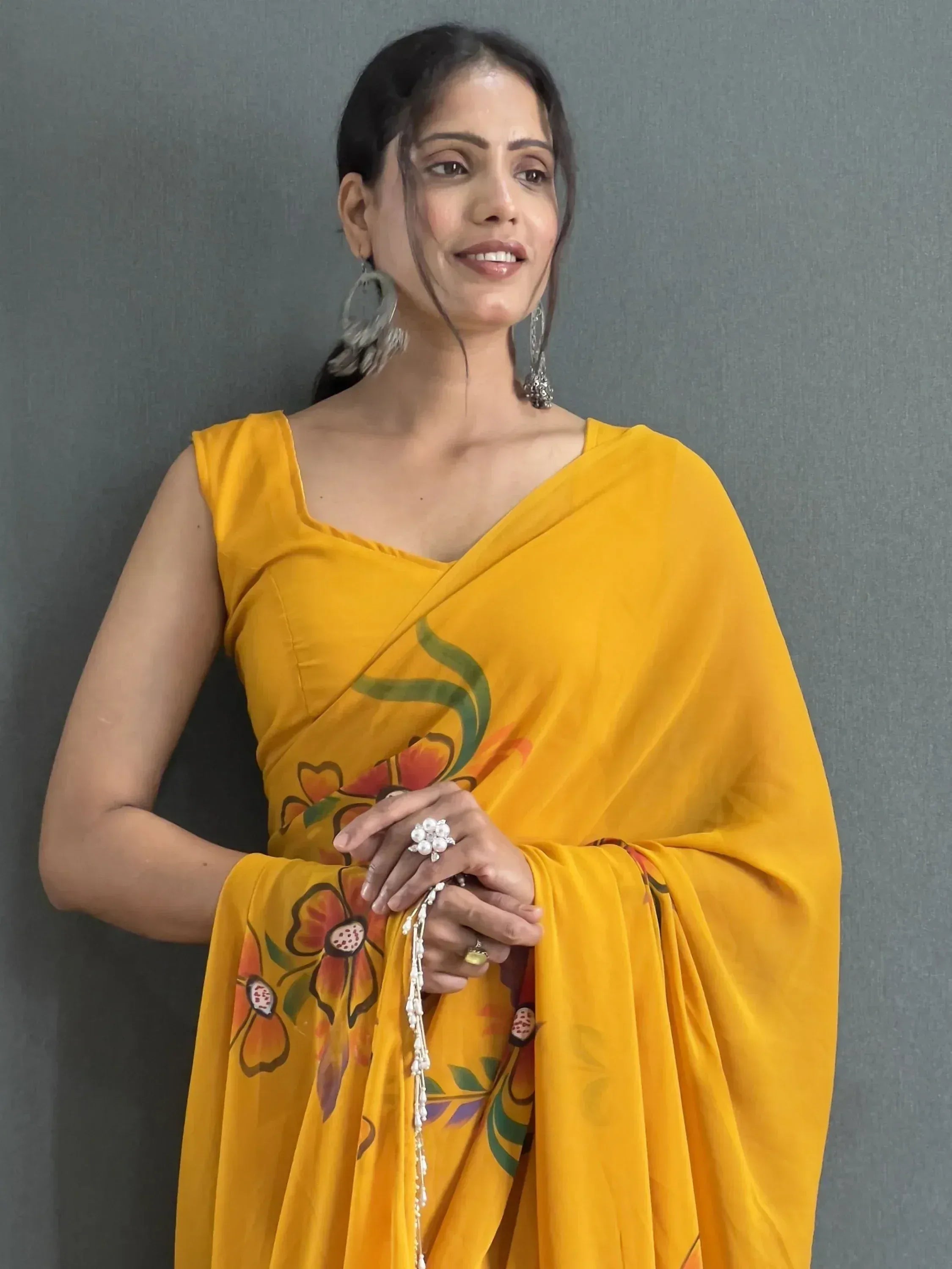 Woman in vibrant yellow floral saree with ethnic jewelry, perfect for Indian occasions