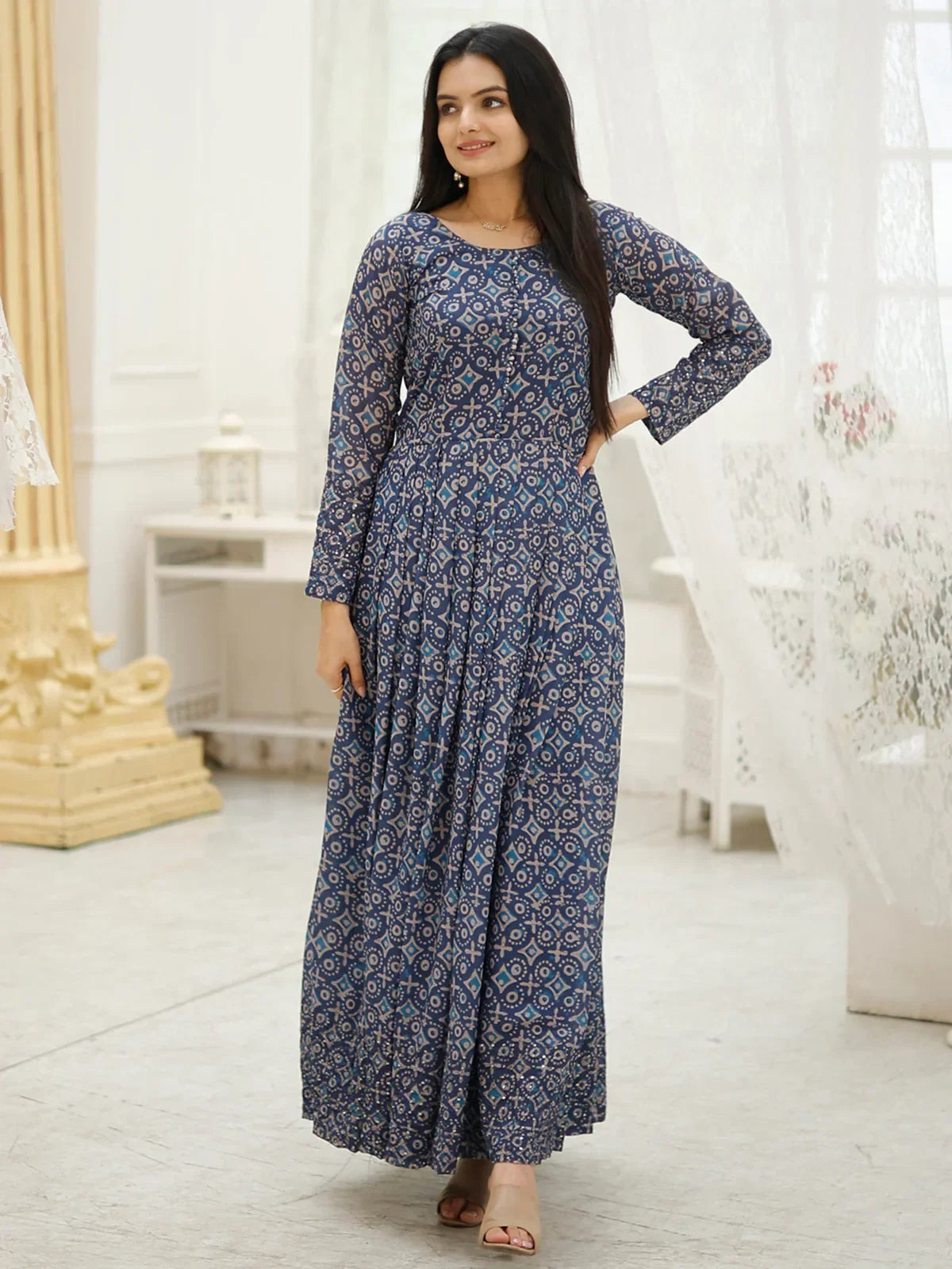 Woman wearing a blue printed ethnic gown with long sleeves in a modern indoor setting