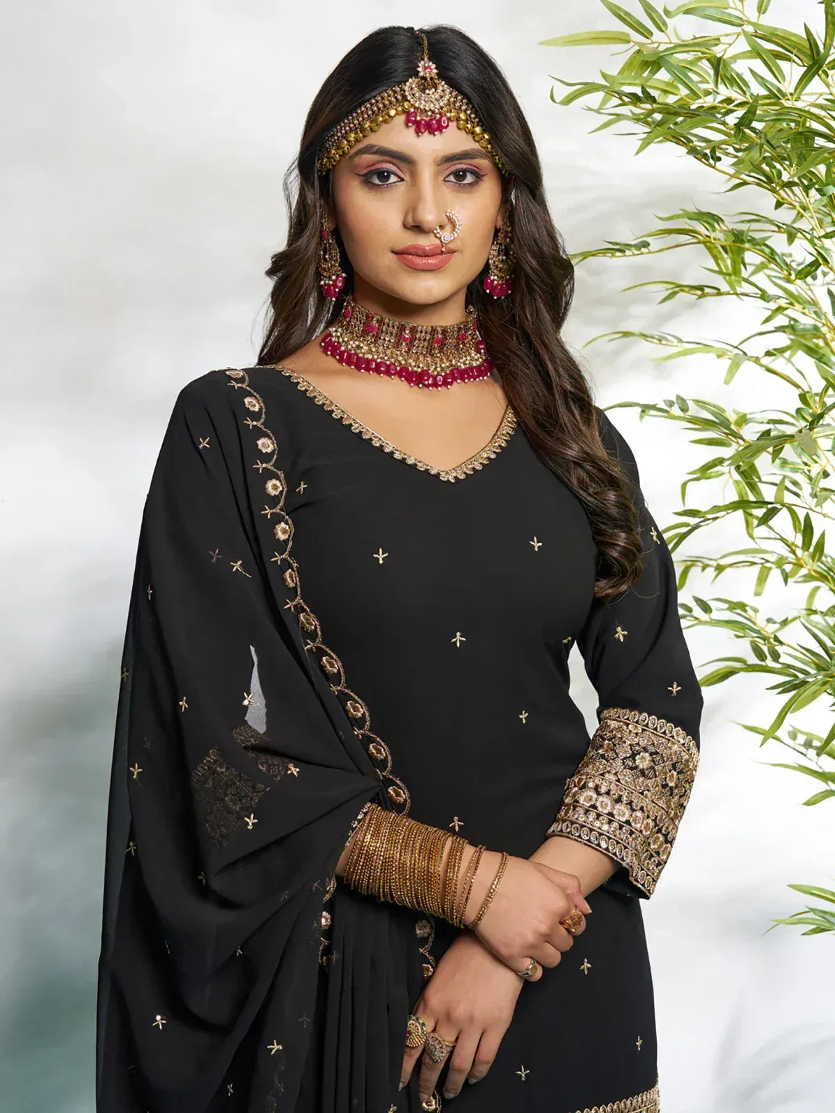Black embroidered salwar kameez with gold detailing and red jewelry, perfect for Indian ethnic wear occasions.