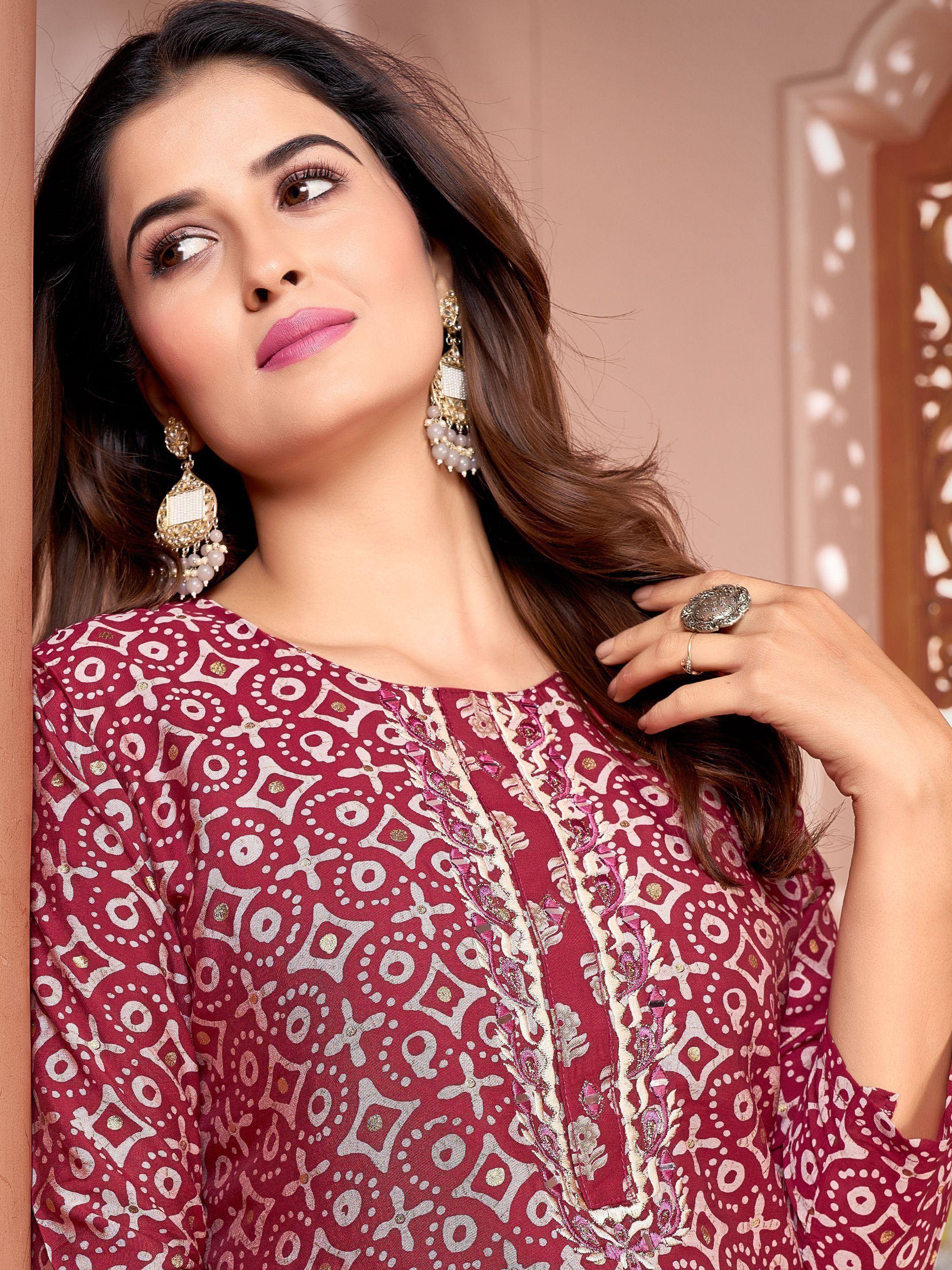 Woman in maroon printed ethnic kurti with gold embroidery, paired with statement earrings and ring, ideal for festive occasions.