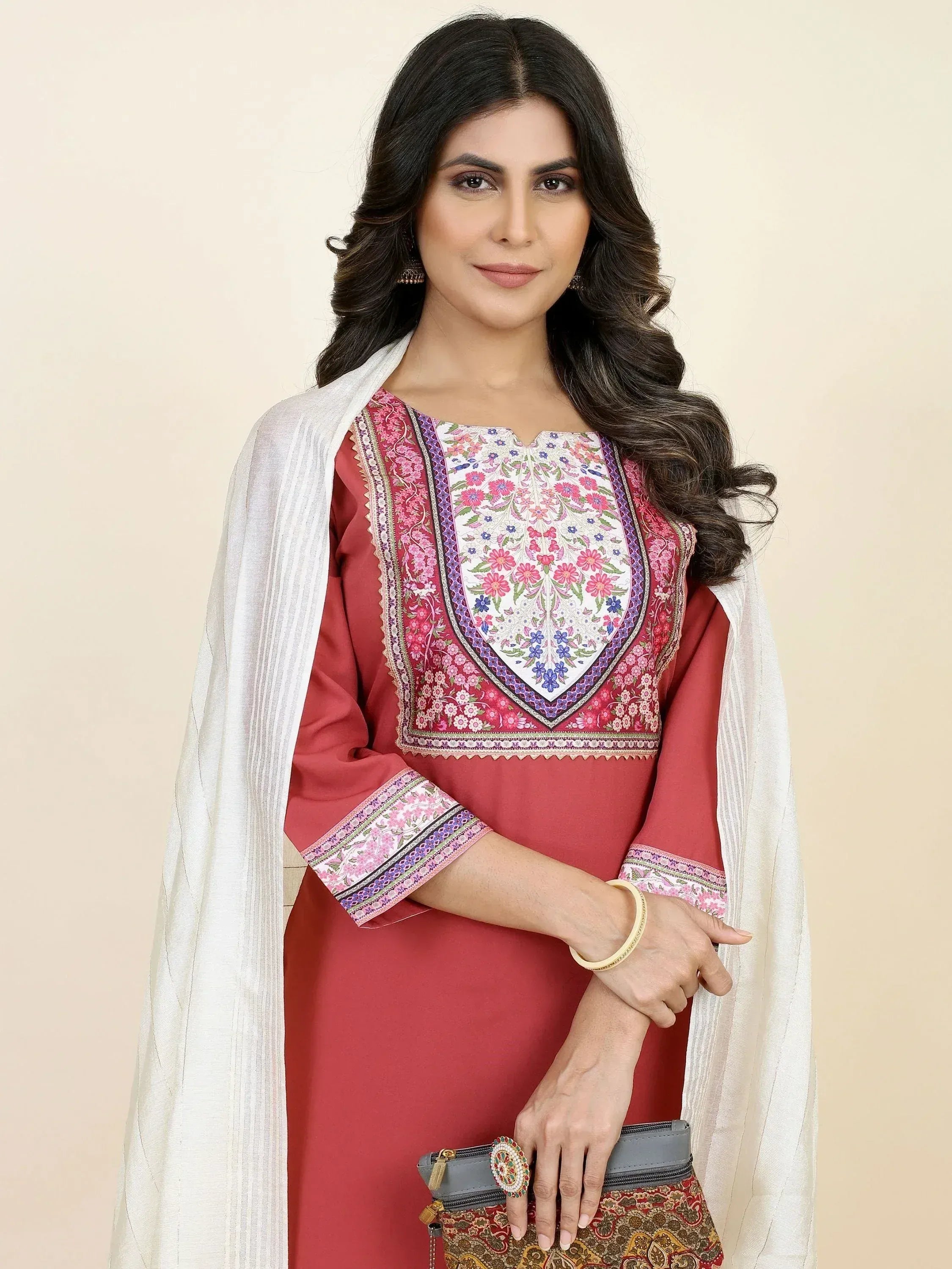 Woman in maroon embroidered ethnic kurti with white dupatta, holding a clutch bag