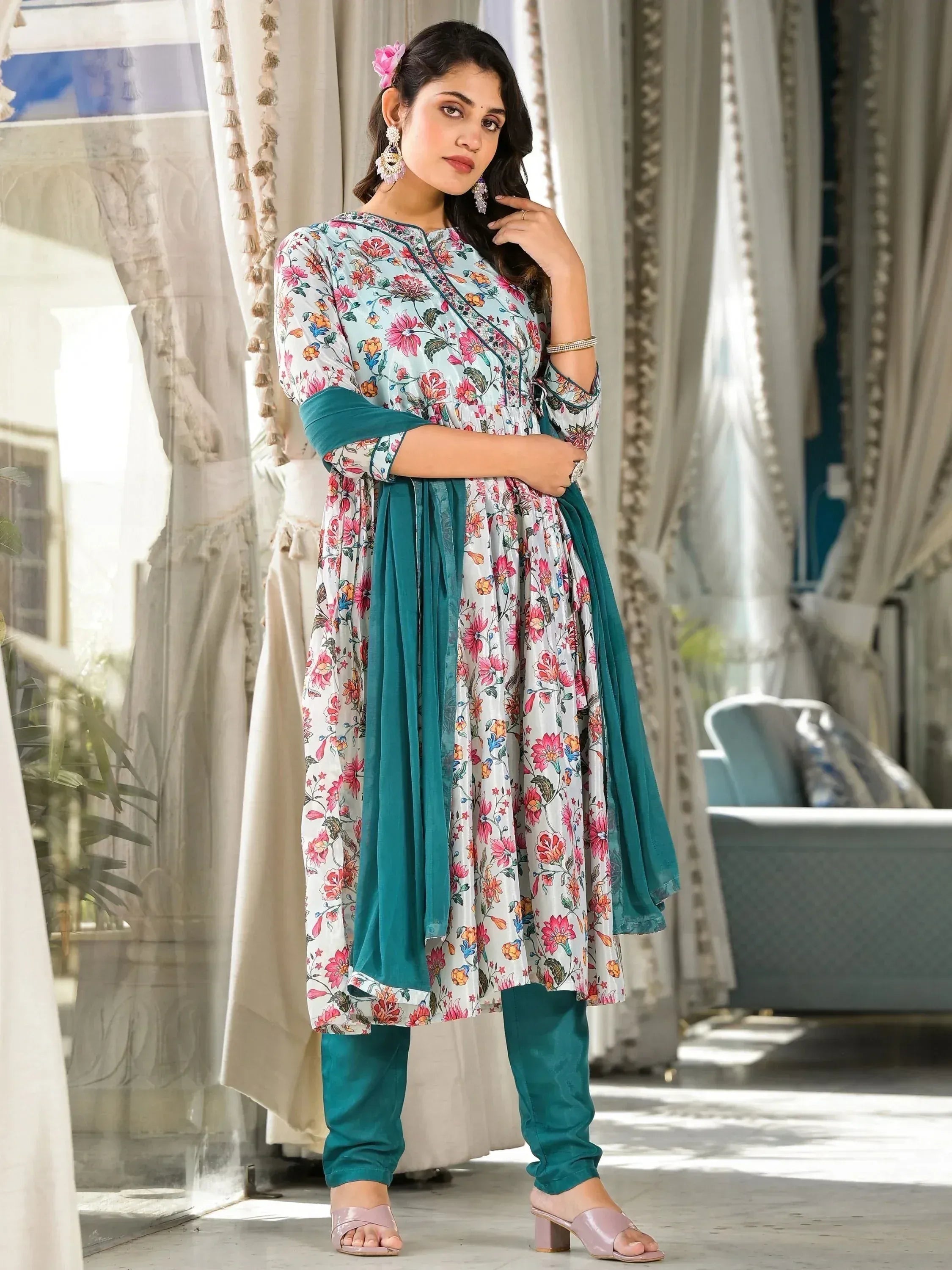 Woman wearing floral printed salwar kameez with teal dupatta and churidar in elegant setting
