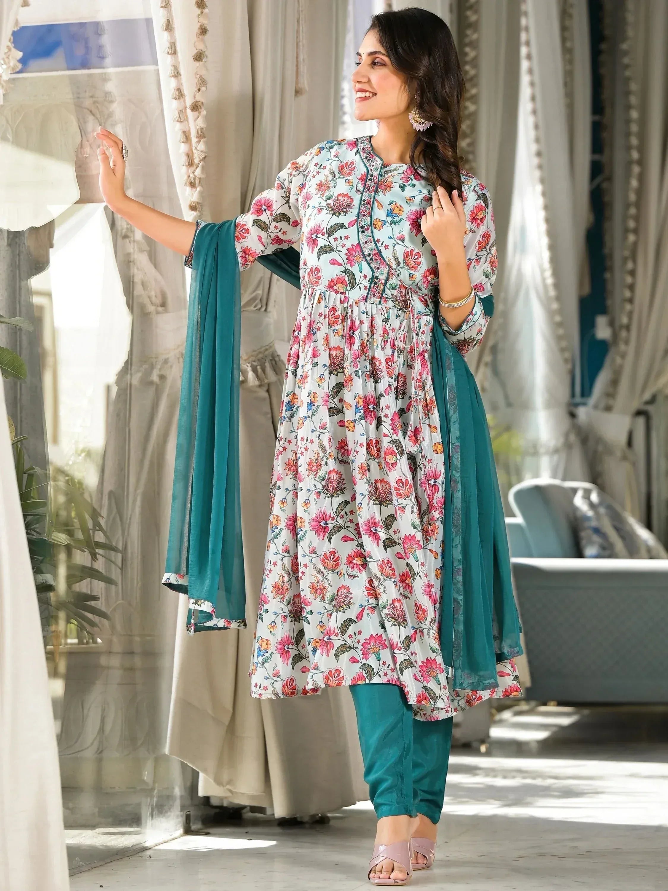 Woman in floral printed salwar kameez with teal dupatta and churidar, posing indoors
