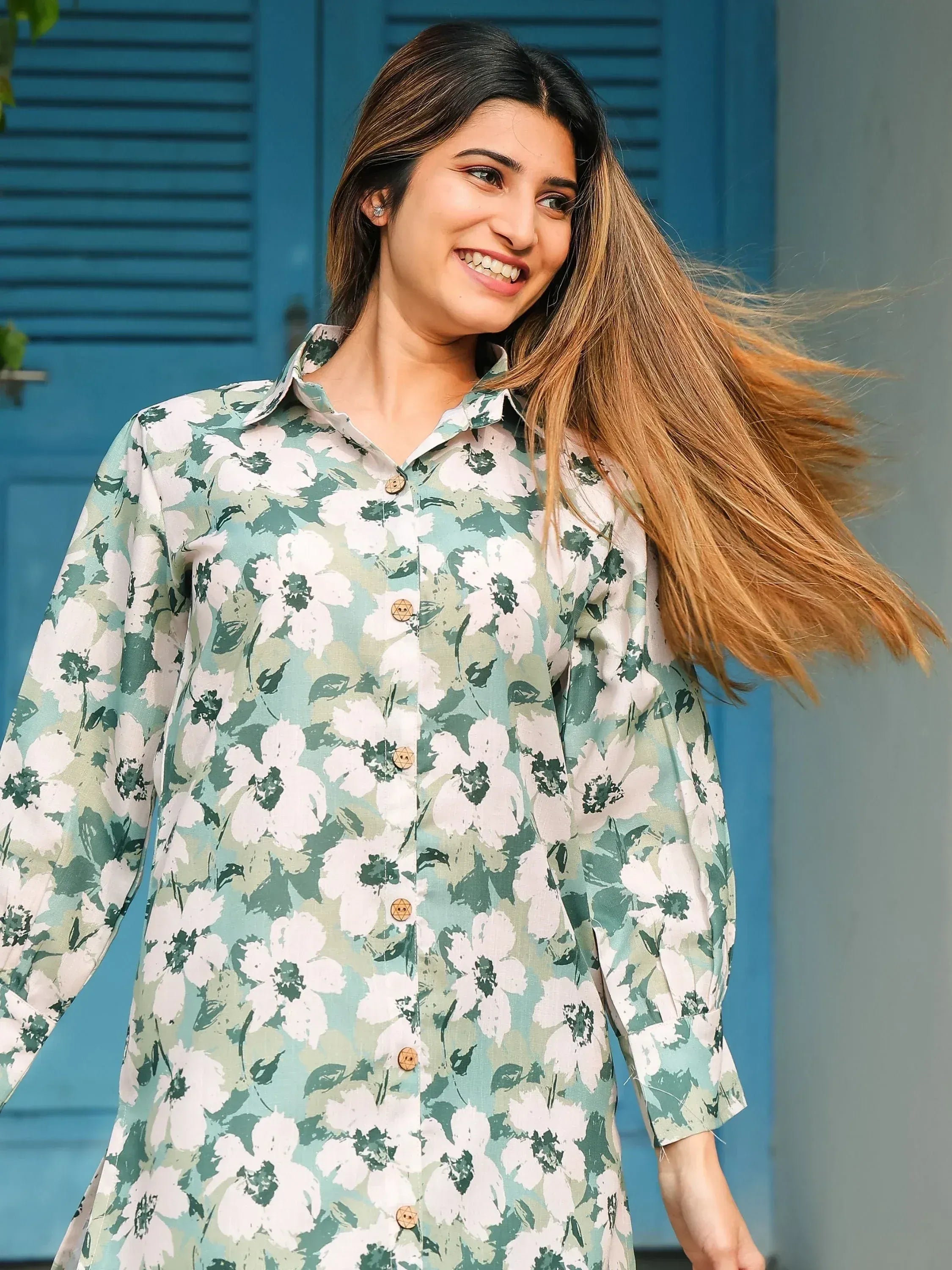 Woman in green and white floral ethnic kurta with wooden buttons, smiling outdoors
