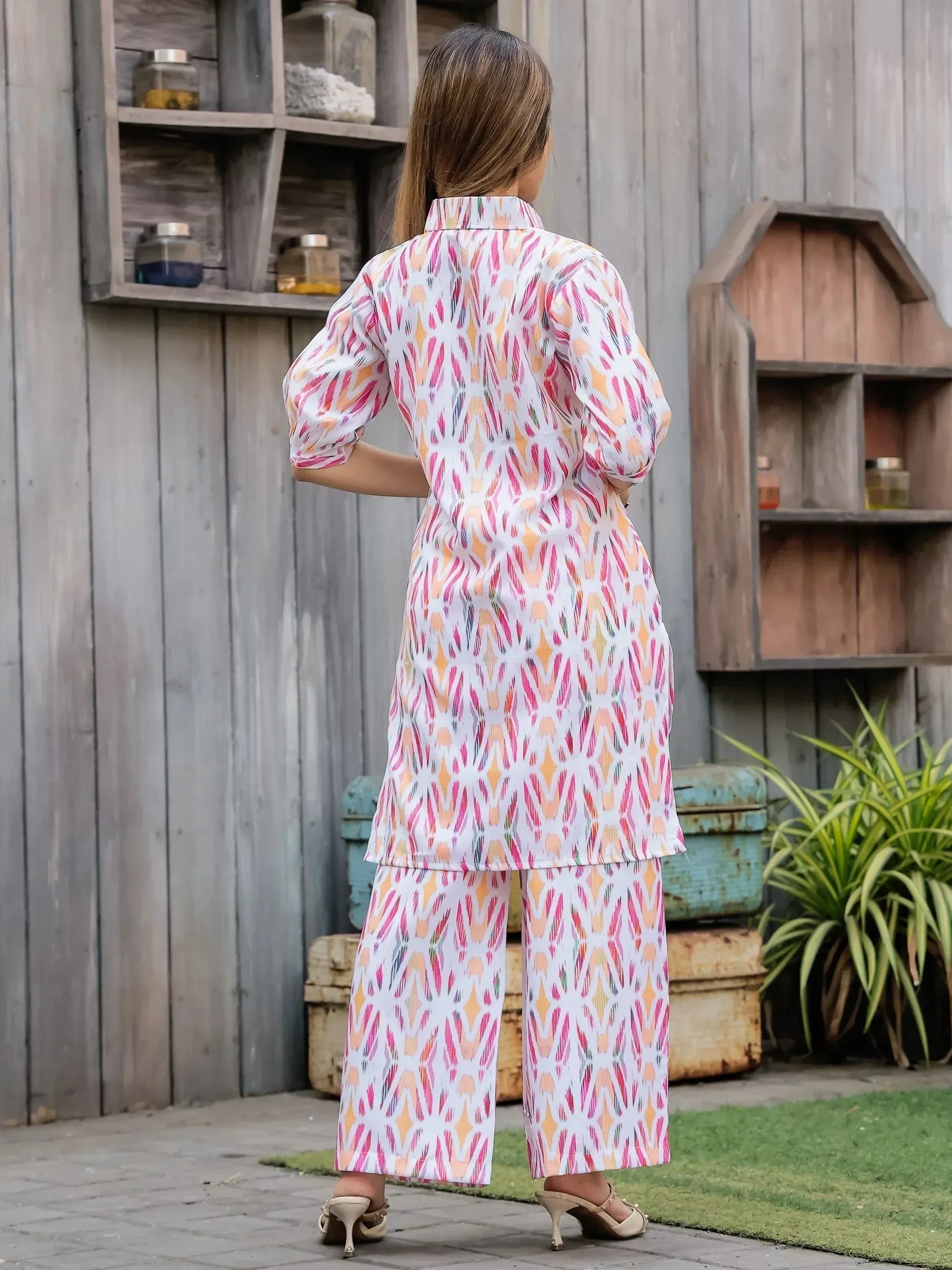 Woman in colorful printed ethnic kurta set with palazzo pants, back view, wooden backdrop