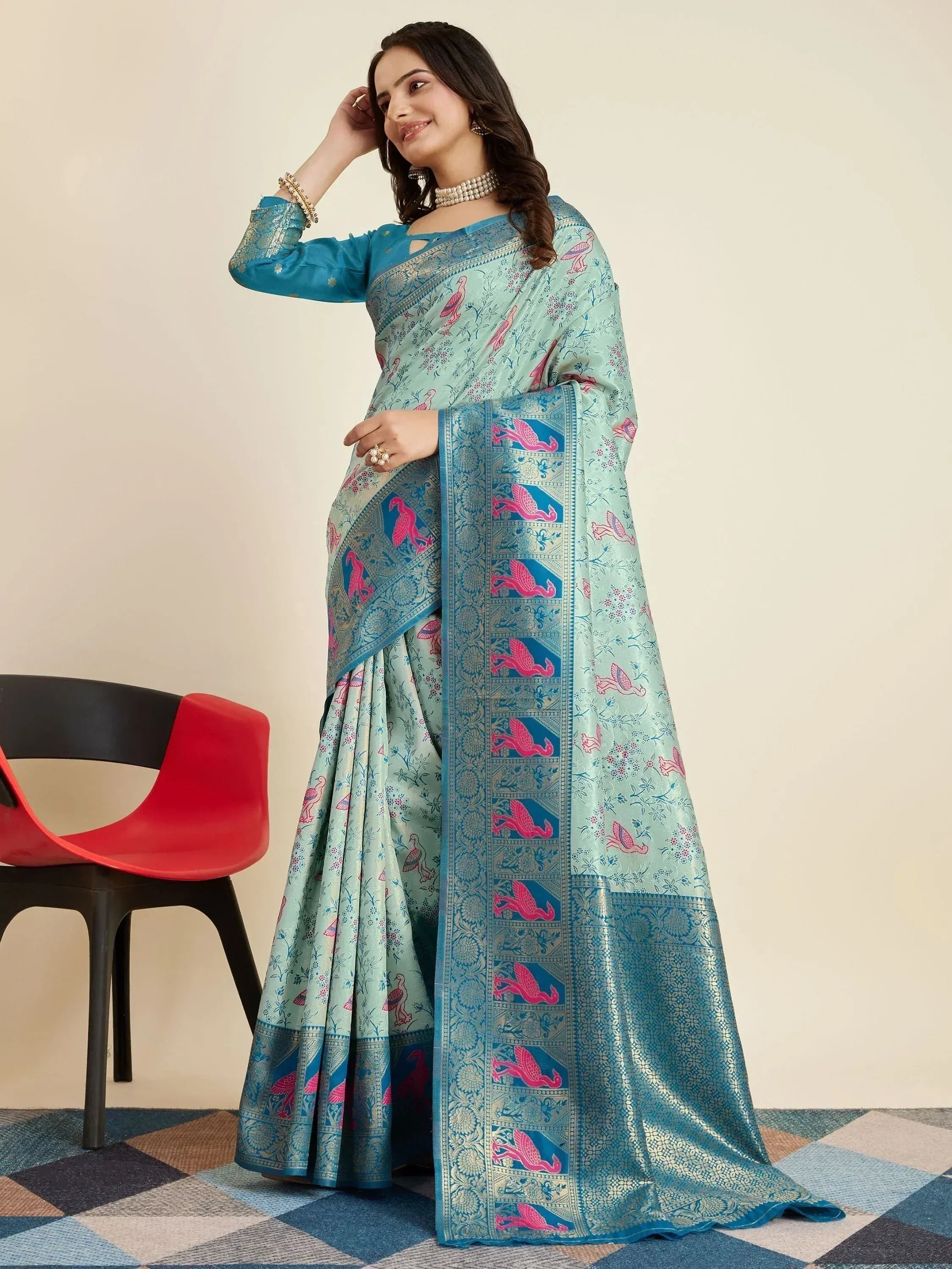 Woman in mint green saree with pink bird print and blue border, paired with matching blouse for ethnic wear