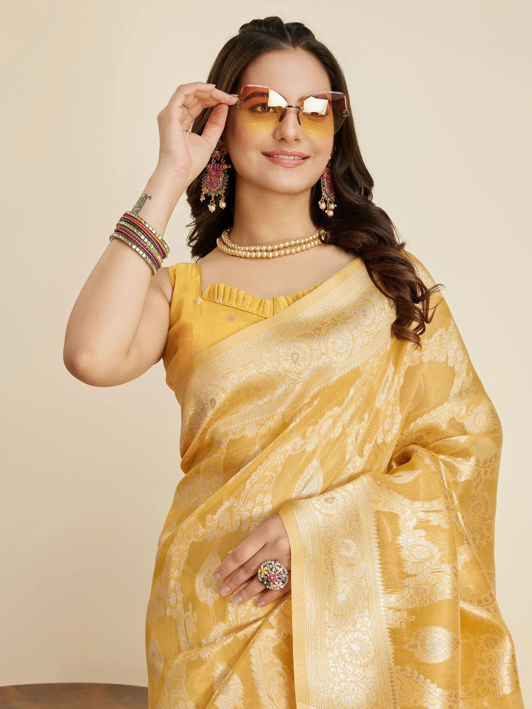 Yellow designer saree with gold embroidery, paired with statement jewelry and sunglasses for ethnic wear