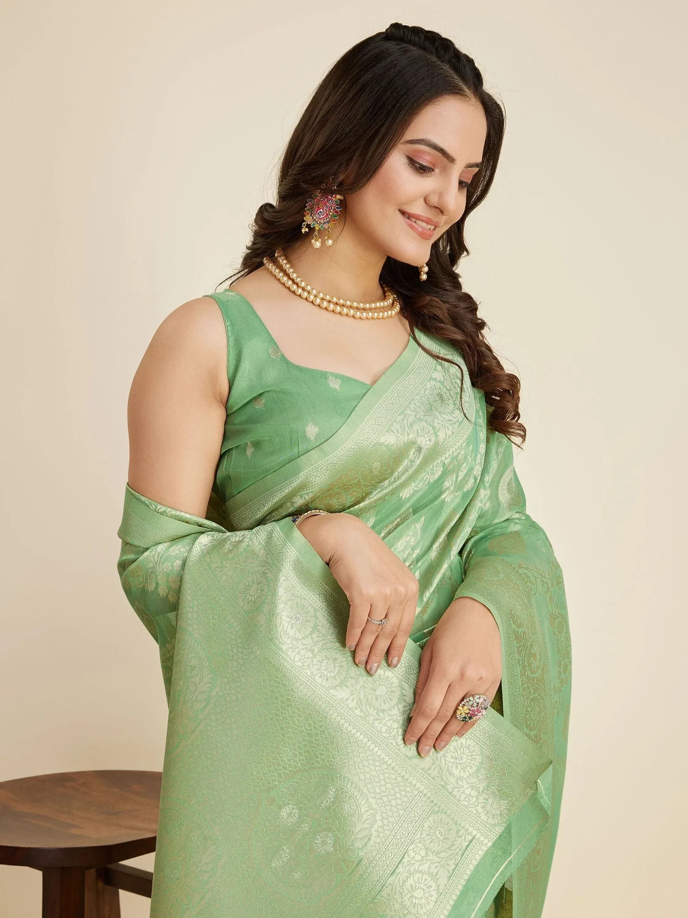 Woman in elegant green saree with gold embroidery, styled with pearl jewelry for Indian ethnic wear