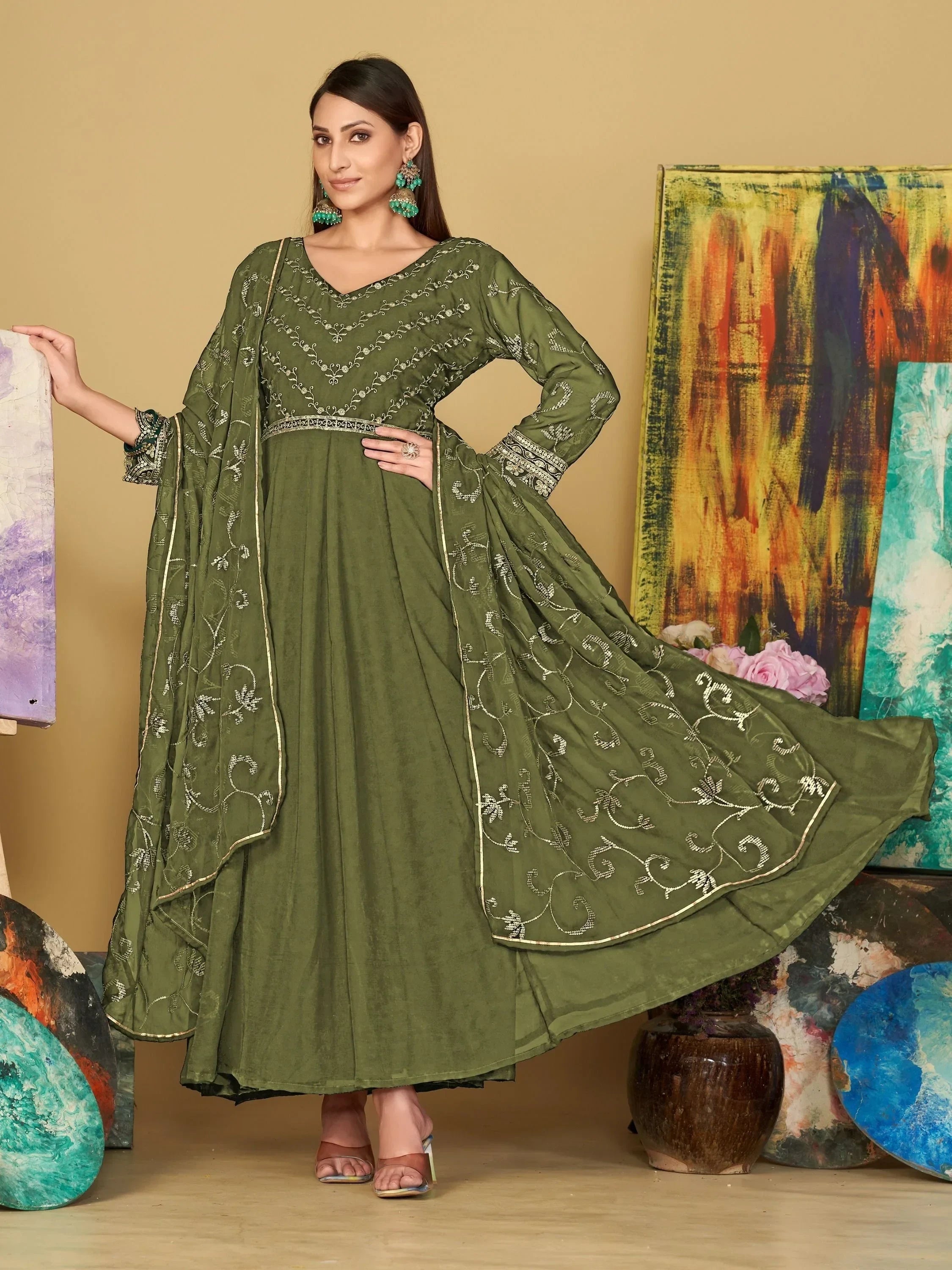Woman in olive green embroidered ethnic gown with dupatta, standing indoors