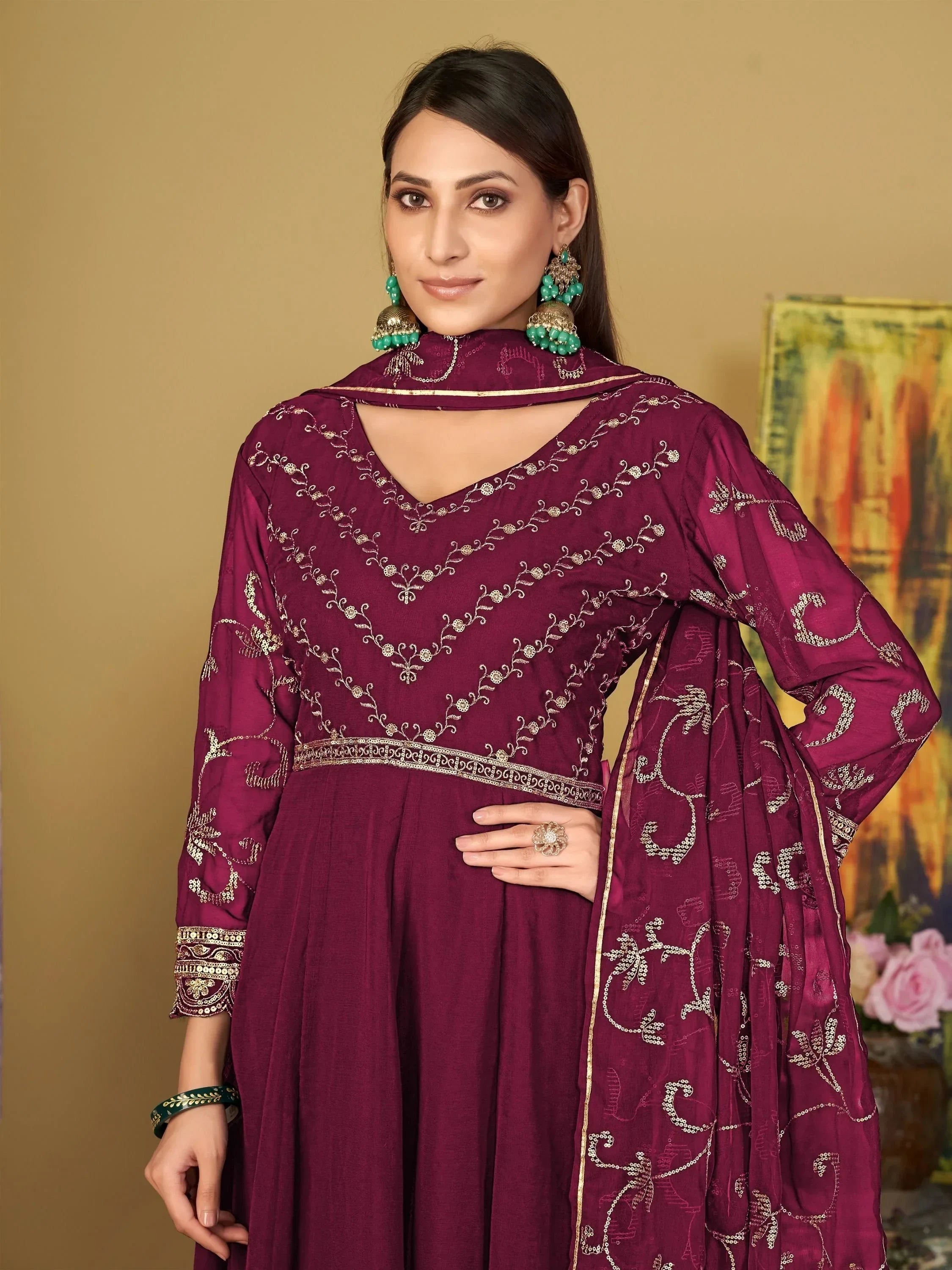 Woman in maroon embroidered ethnic gown with matching dupatta and statement earrings