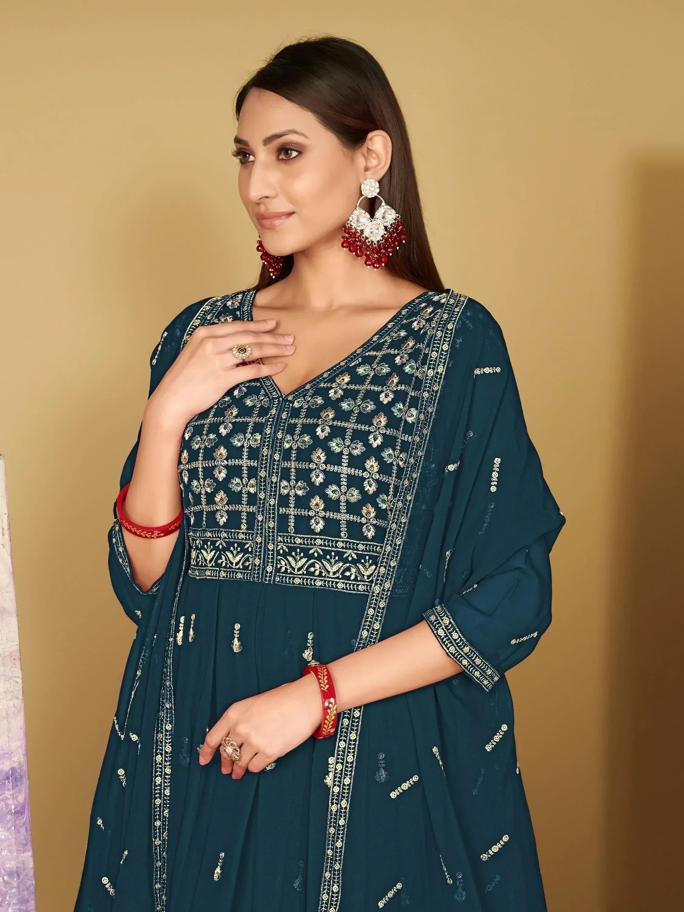 Teal embroidered anarkali suit with gold detailing, paired with red bangles and statement earrings.