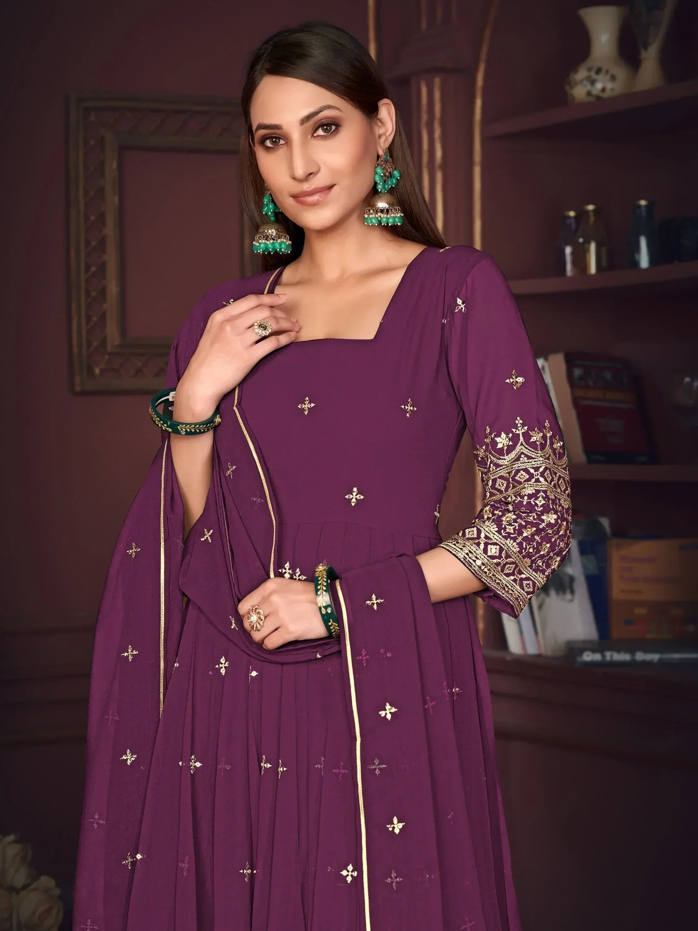 Purple ethnic anarkali suit with gold embroidery and green jewelry, perfect for Indian occasions