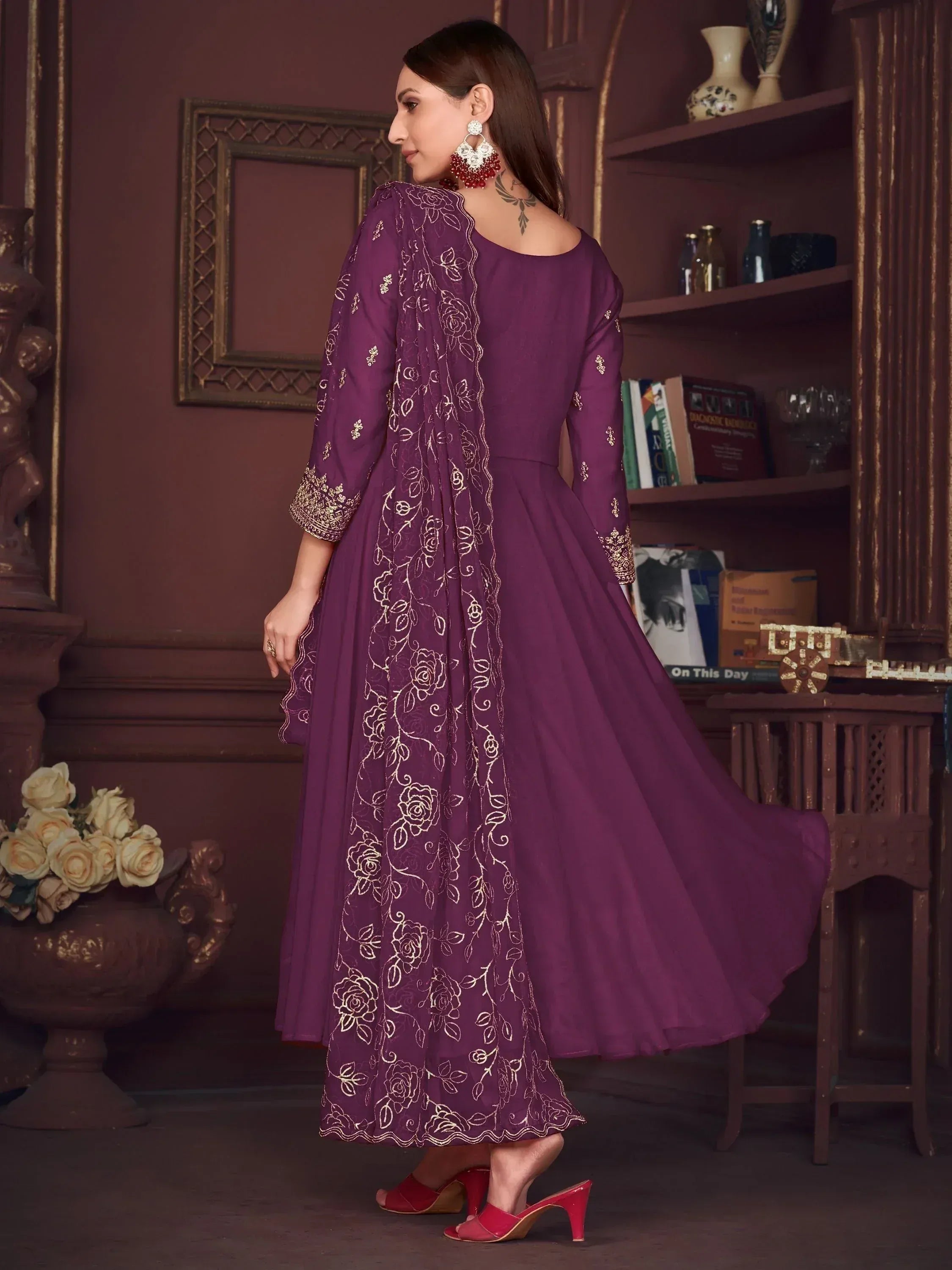 Purple ethnic gown with gold floral embroidery, paired with red heels for festive occasions.