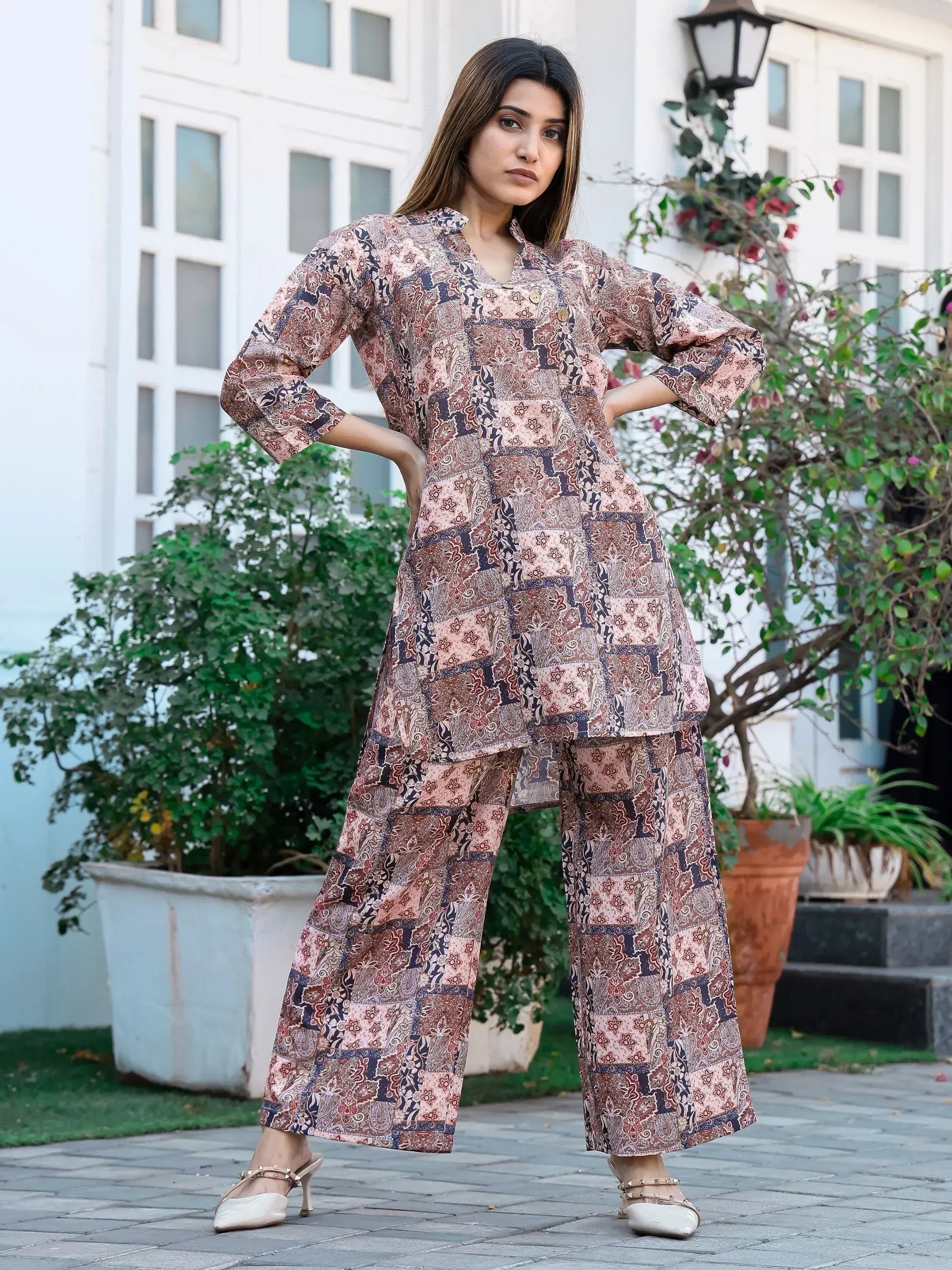 Woman in printed ethnic salwar kameez with wide pants, floral garden backdrop