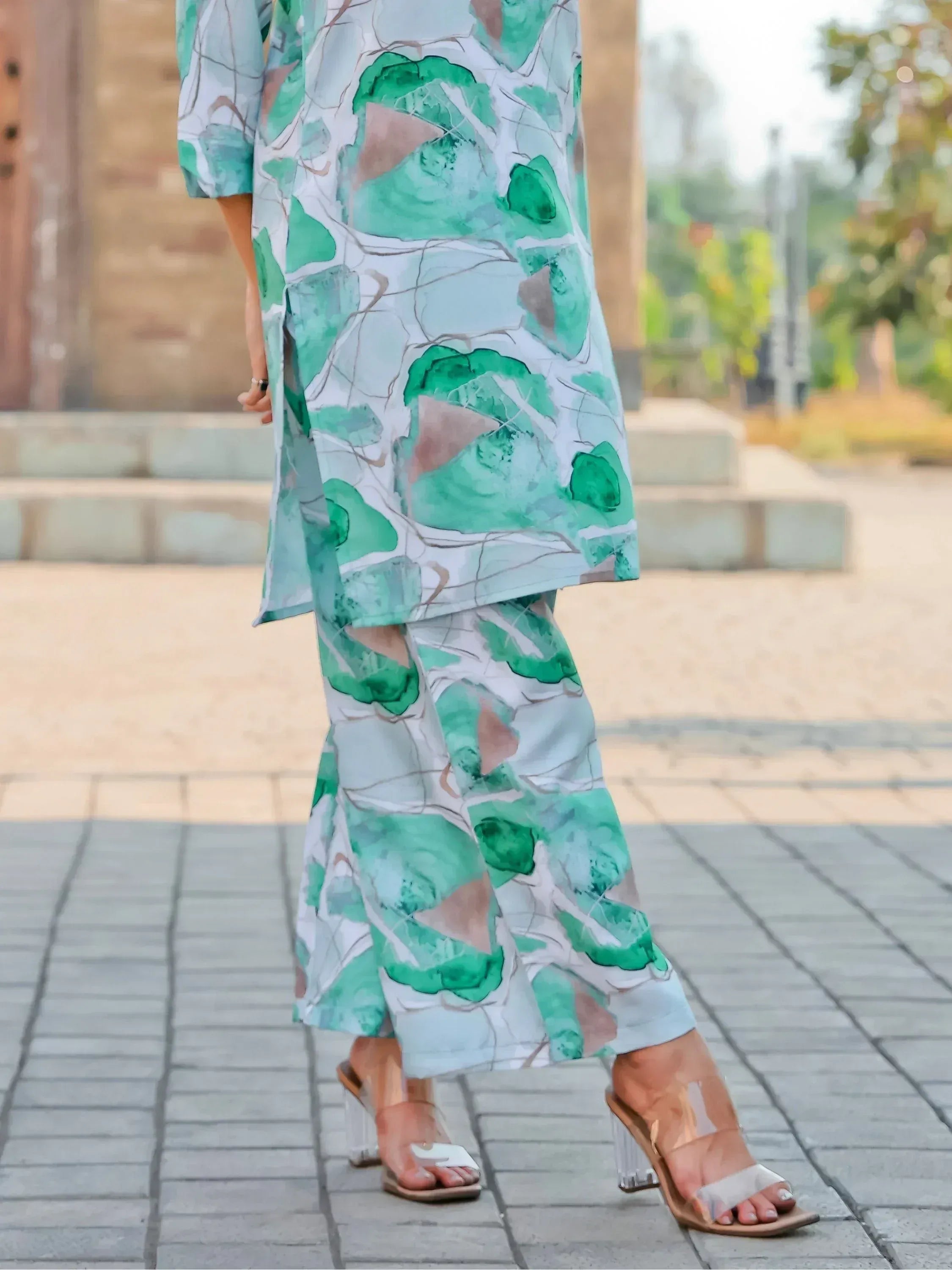 Woman wearing green abstract print palazzo suit with clear heel sandals outdoors