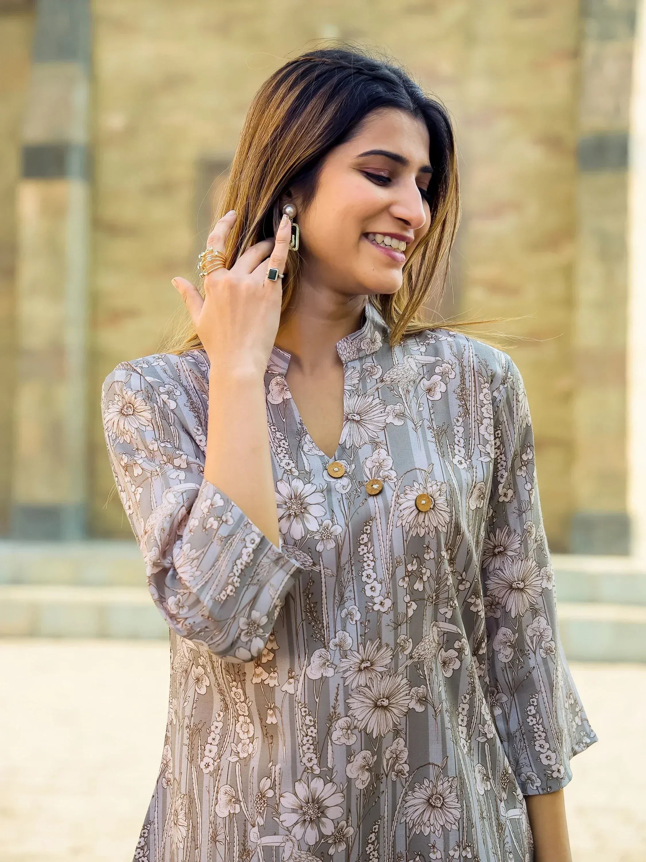 Woman in floral print ethnic kurta with bird motifs, styled with statement earrings and rings